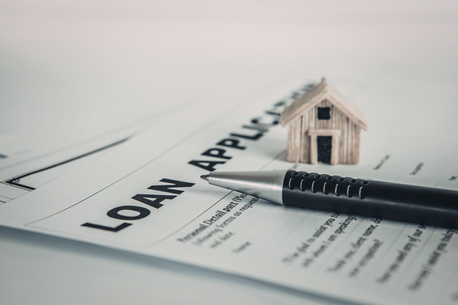 Loan application document with pen and house model — loan sizing and DSCR