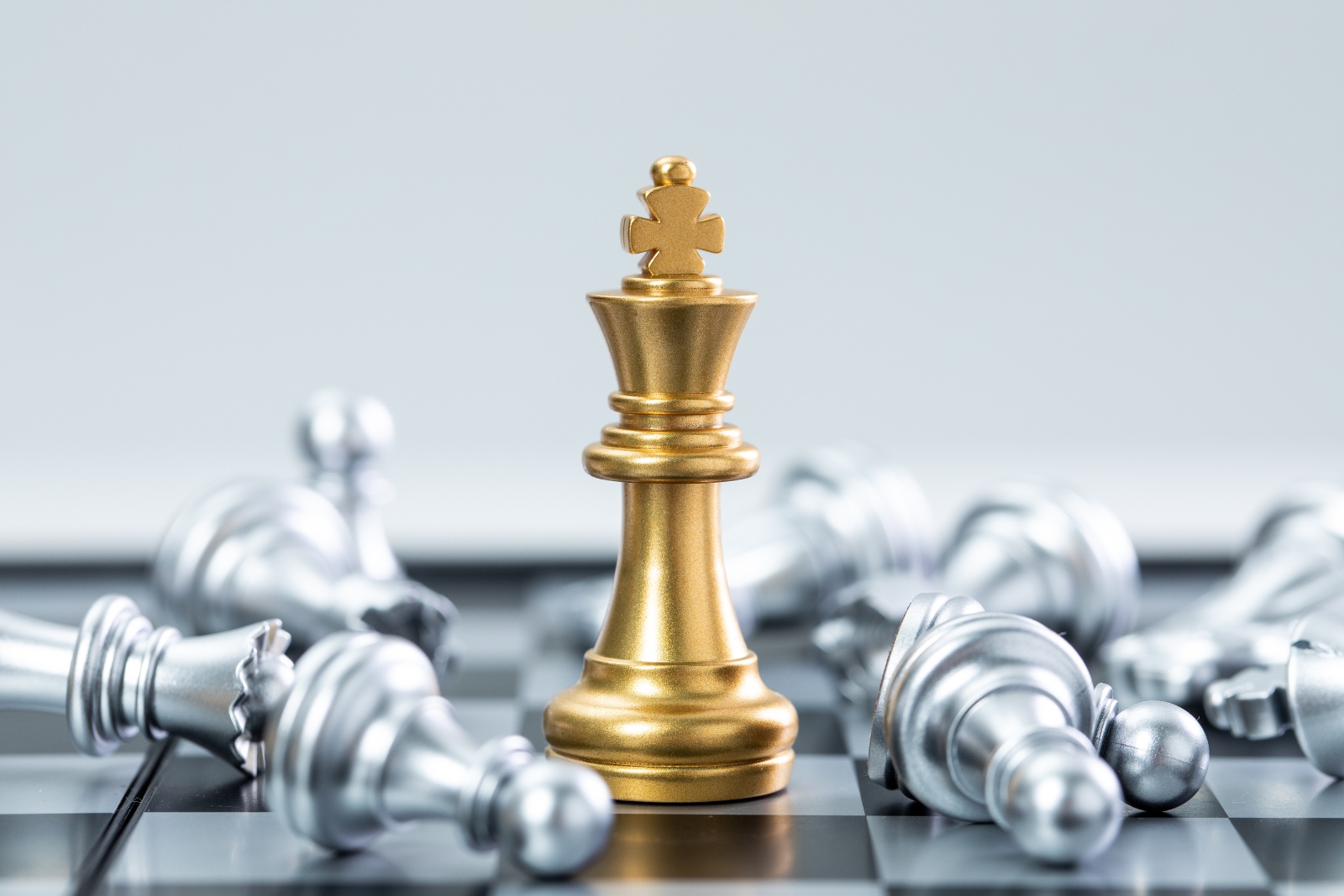 Gold king chess piece standing among fallen silver pieces — Hold vs Sell advisory decision