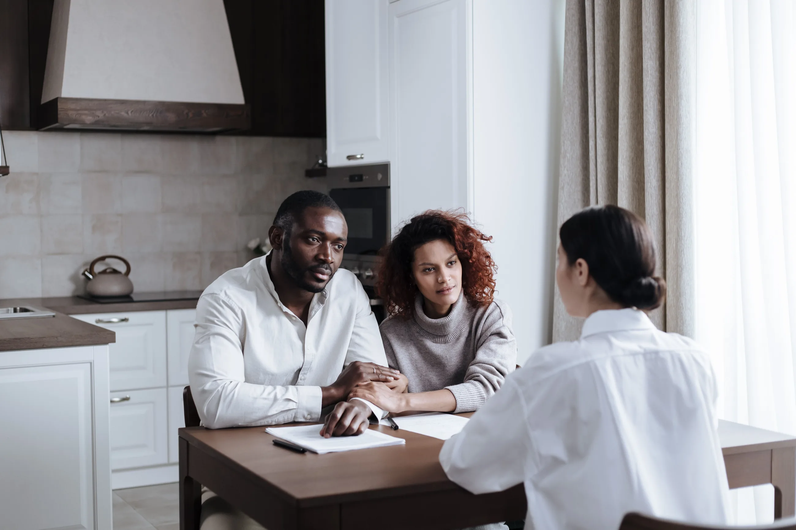 A couple at the kitchen table reviewing paperwork with the project lead