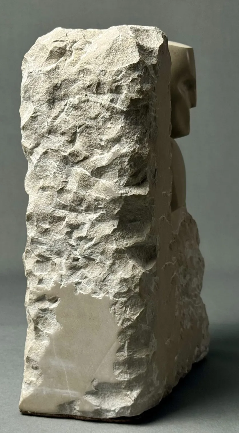 Skulptur eines Gesichts, das aus grobem Stein herausgearbeitet ist, seitliche Ansicht.