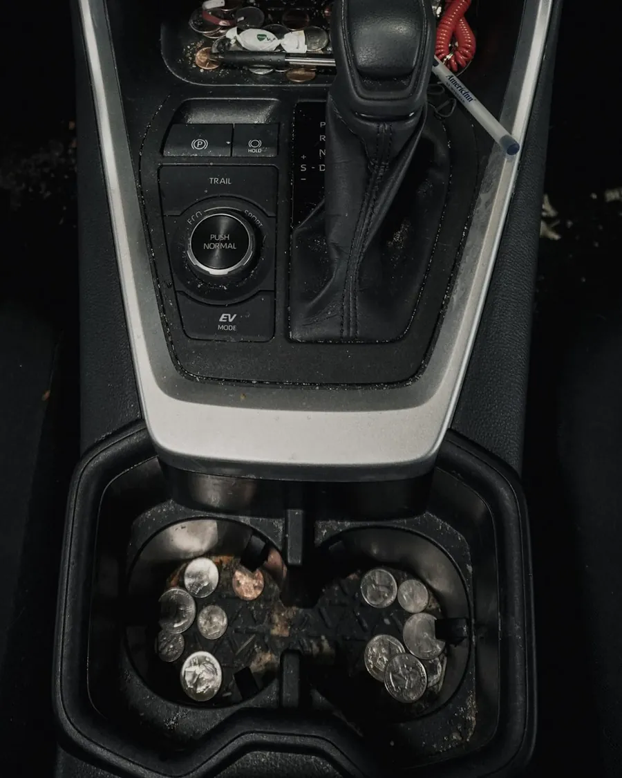 Car cupholder console before detailing — coins, crumbs and debris
