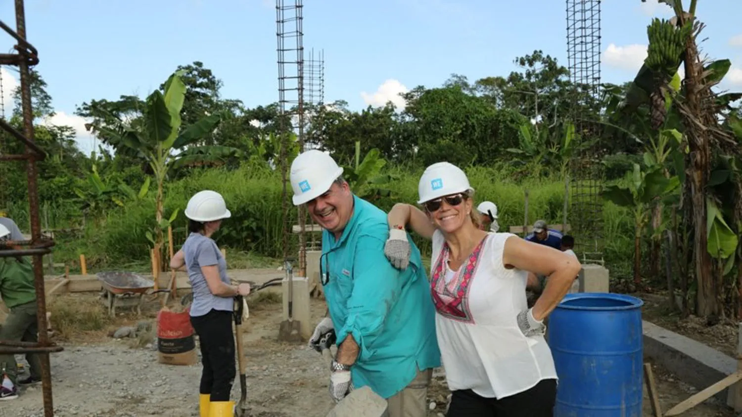 a couple of people standing next to each other working on a building