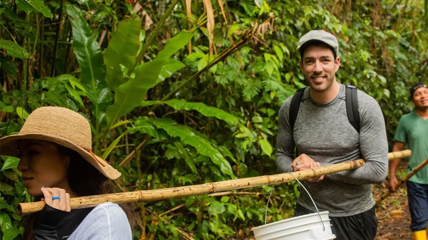 a man carrying a wooden stick across a forest