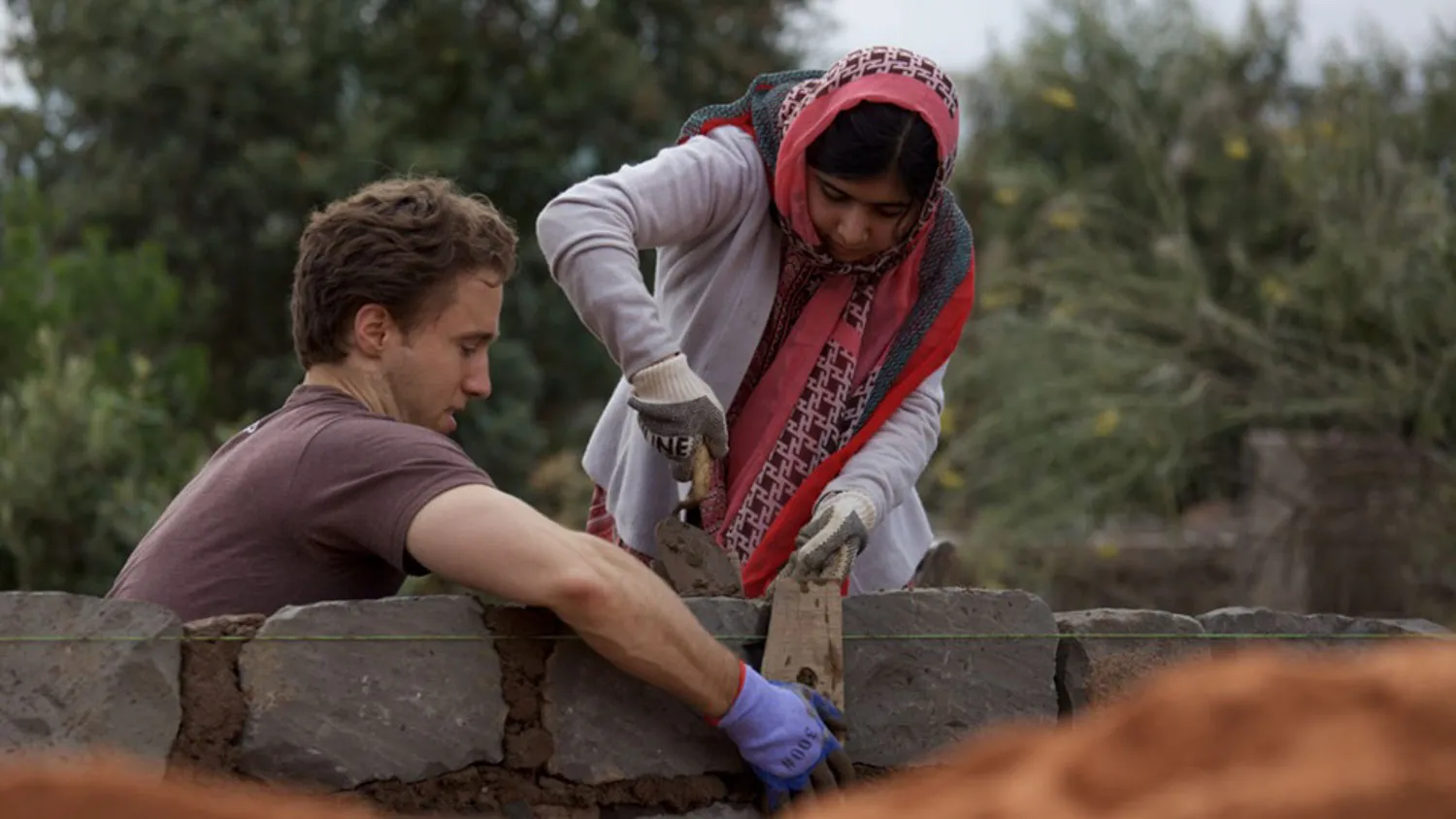 a man and a woman working on a brick wall