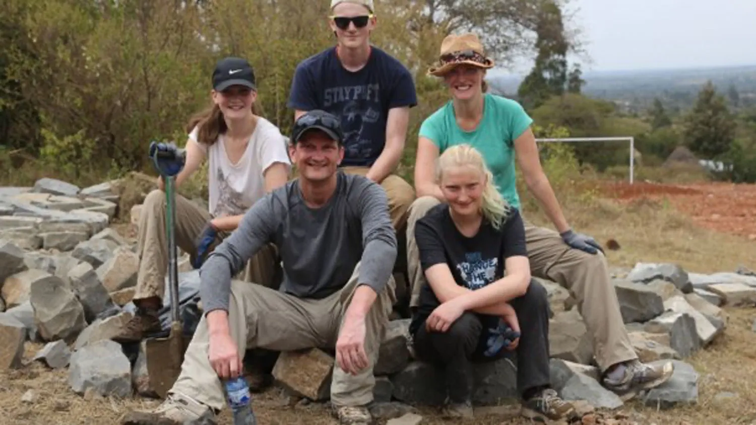 a group of people sitting on top of a pile of rocks