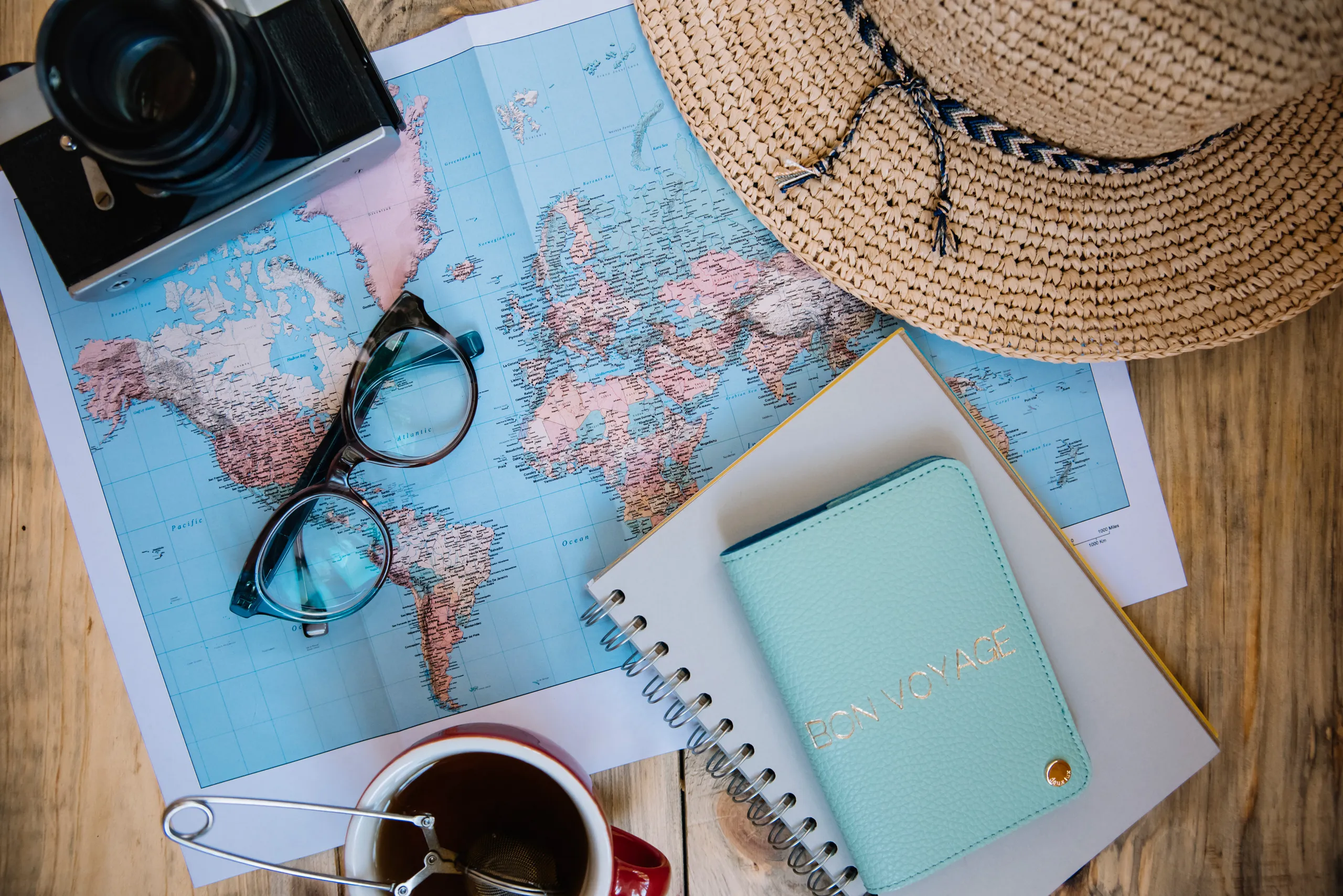 A travel planning flat lay with a map, camera and notebook