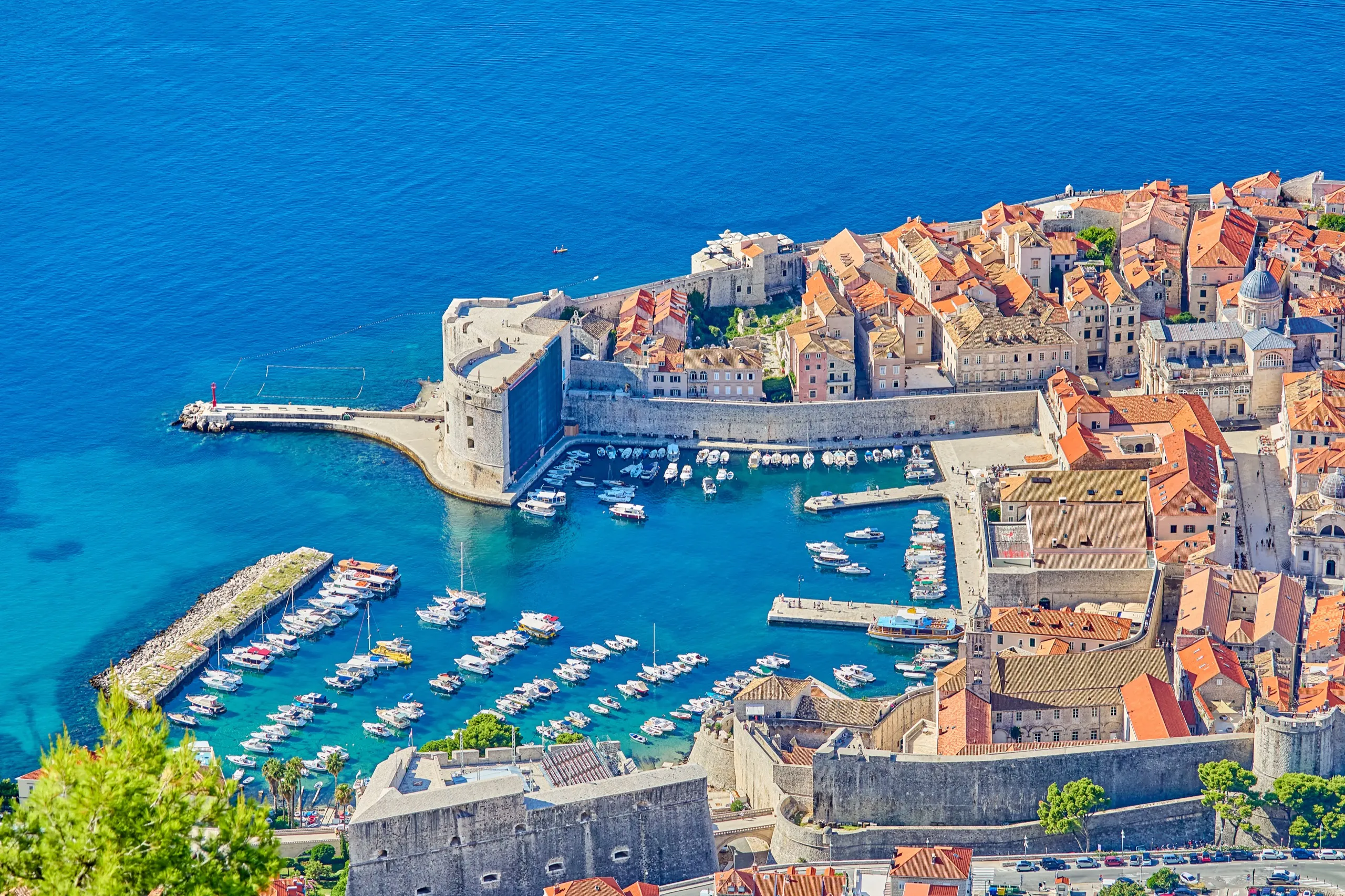 Aerial view of a red-roofed walled old town beside its Adriatic harbor