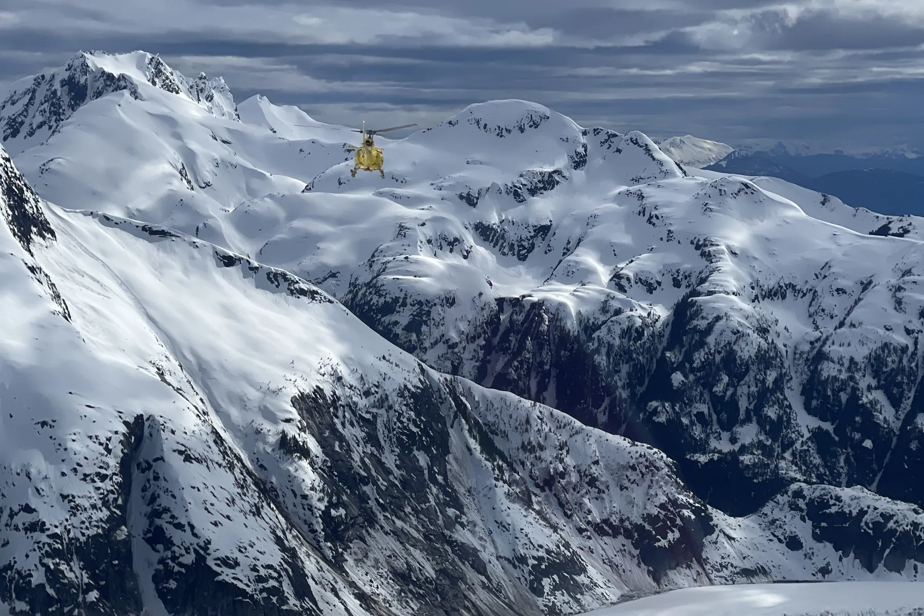 A small aircraft flying over snow-covered mountains and a glacier in Alaska