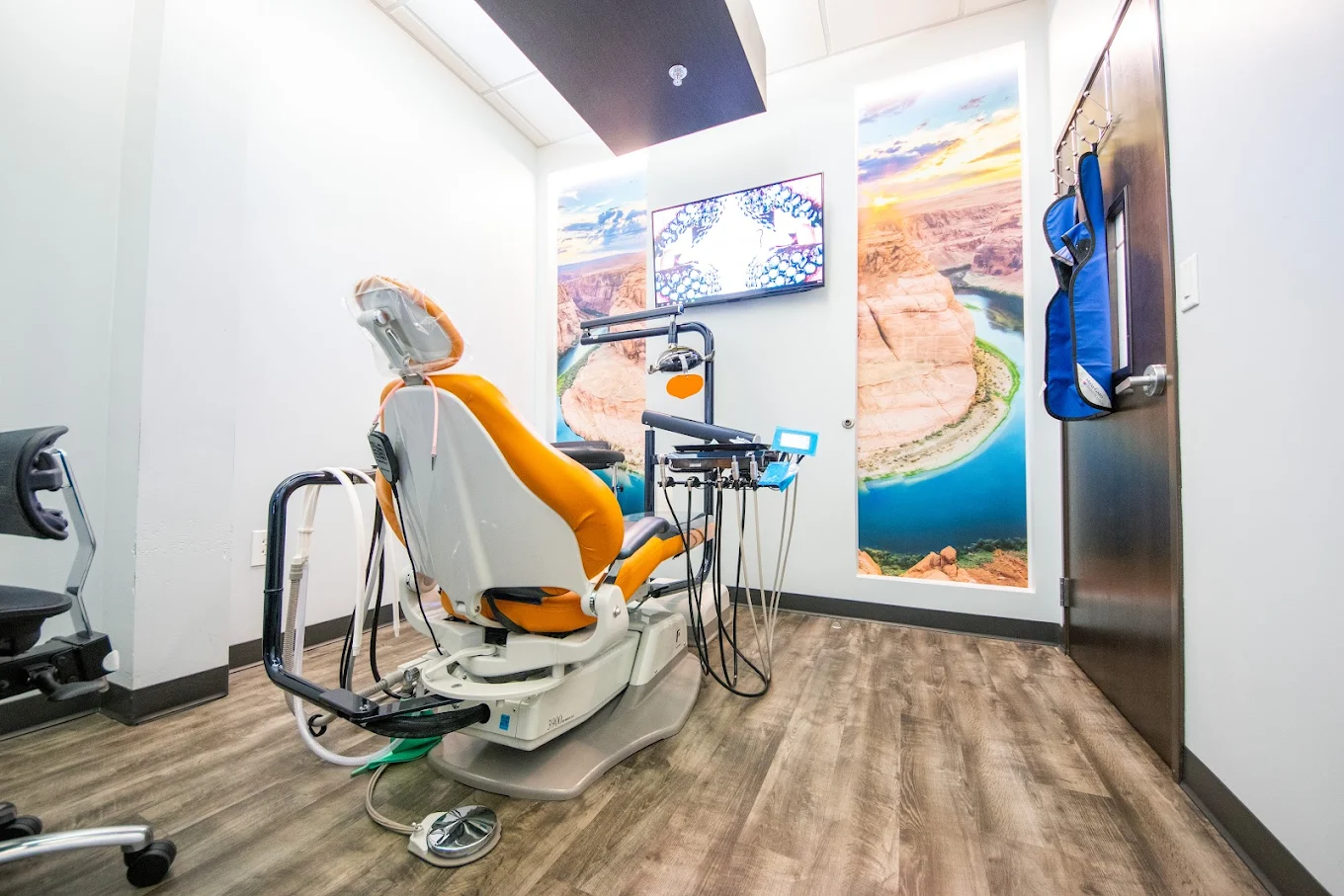 Modern Comfydent Smiles dental treatment room with an orange dental chair, fully equipped with dental instruments and a panoramic canyon mural on the wall