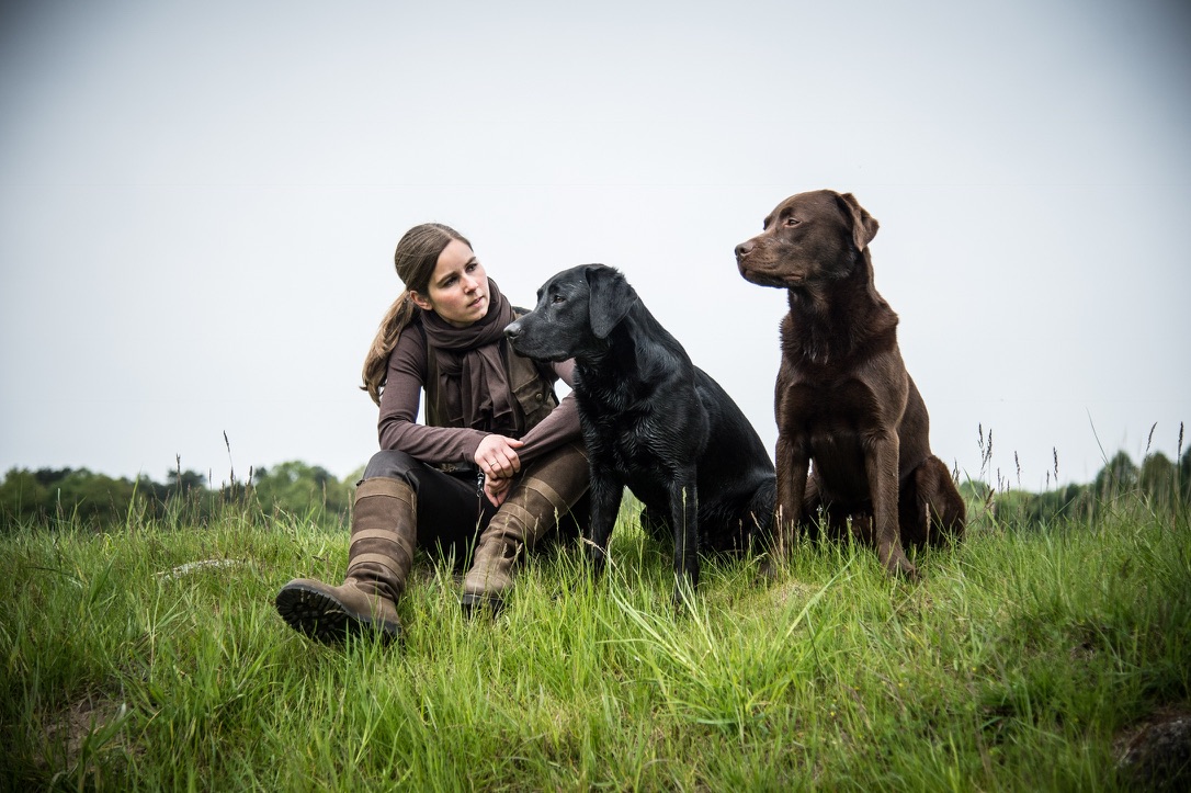 Nina Wolber sitzt im Gras zwischen ihren beiden Labradoren