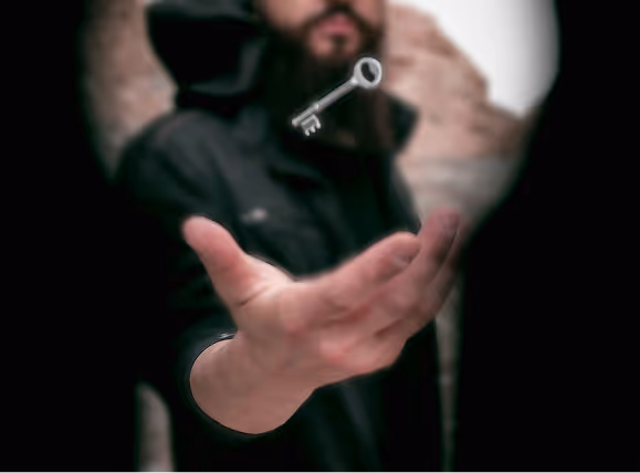 Hand reaching out toward a floating key with a blurred person in the background.