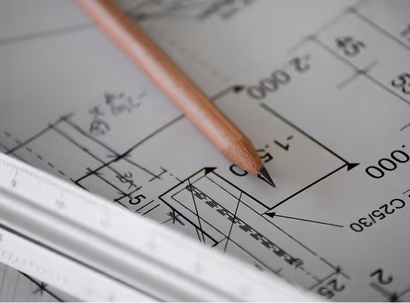Close-up of a pencil and ruler on an architectural blueprint with detailed measurements.