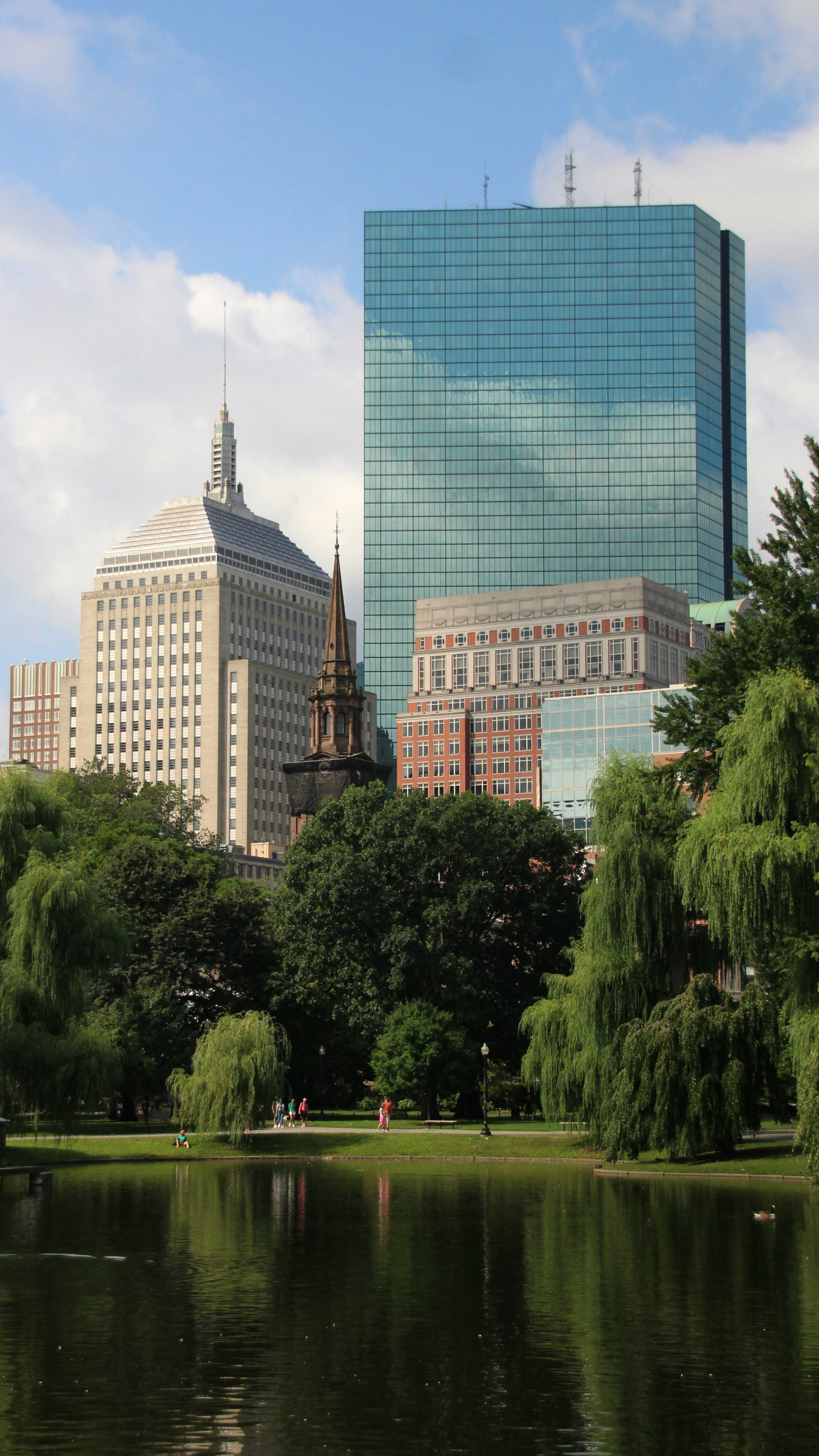 Boston skyline with tall buildings, trees, and water.