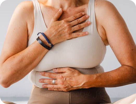 Person in a white tank top holding chest and stomach with both hands.