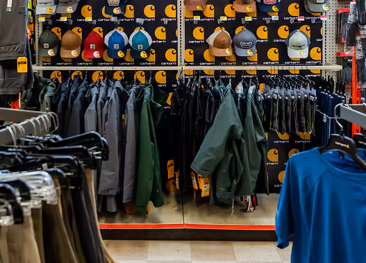 Clothing display with Carhartt jackets, hats, and shirts in a retail store.
