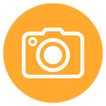 Bílá ikona fotoaparátu na oranžovém kulatém pozadí.