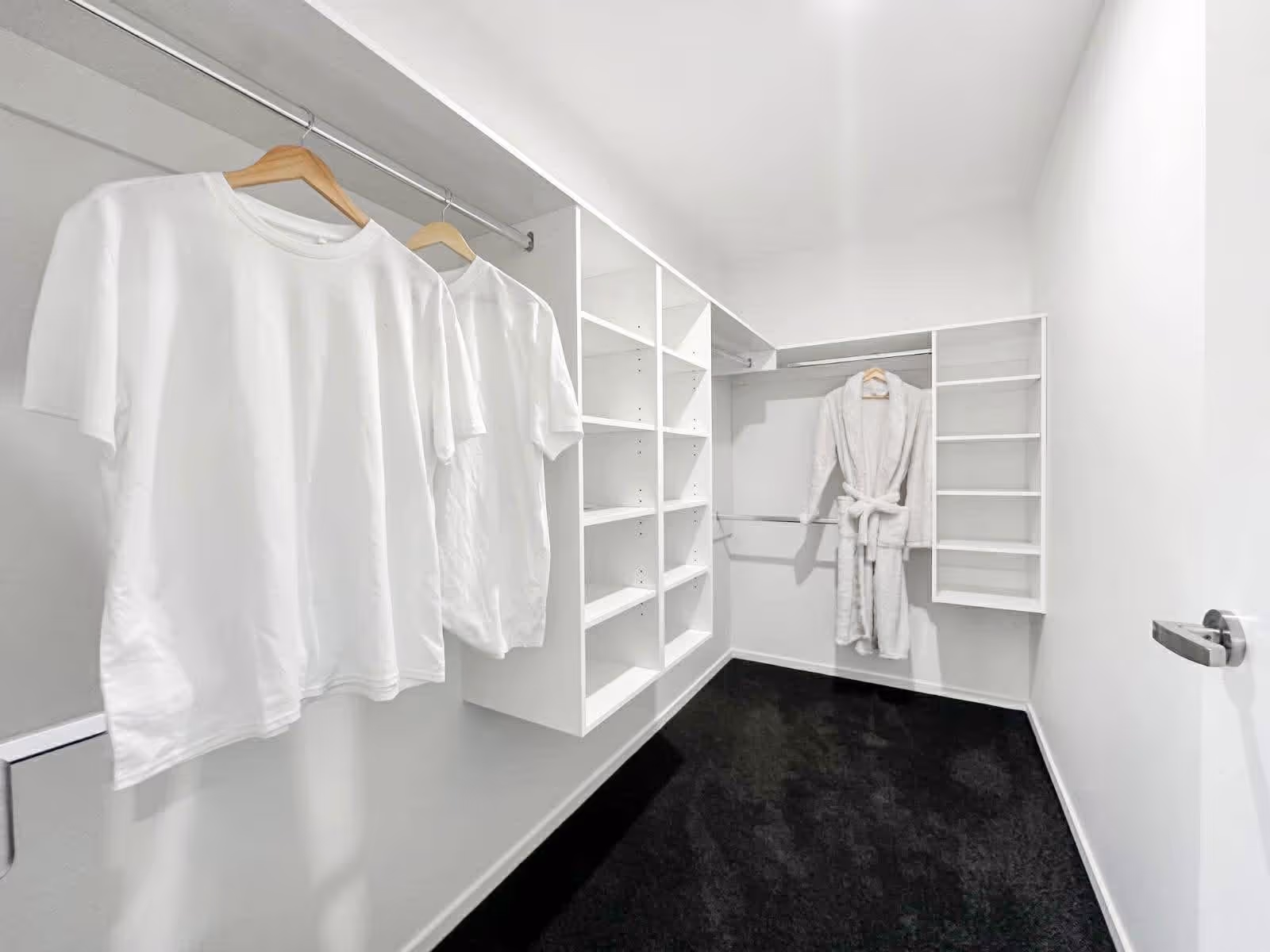 Minimalist walk-in closet with white shelving, two white shirts and a white robe hanging.