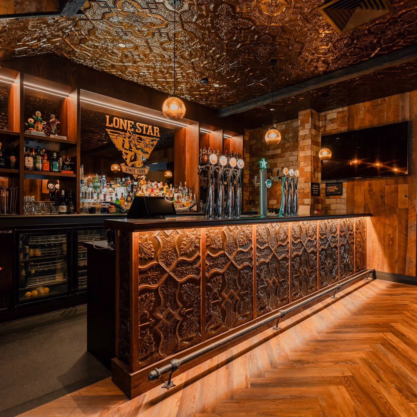 Decorative wooden bar with taps, liquor bottles, ornate ceiling, and Lone Star sign on mirror.