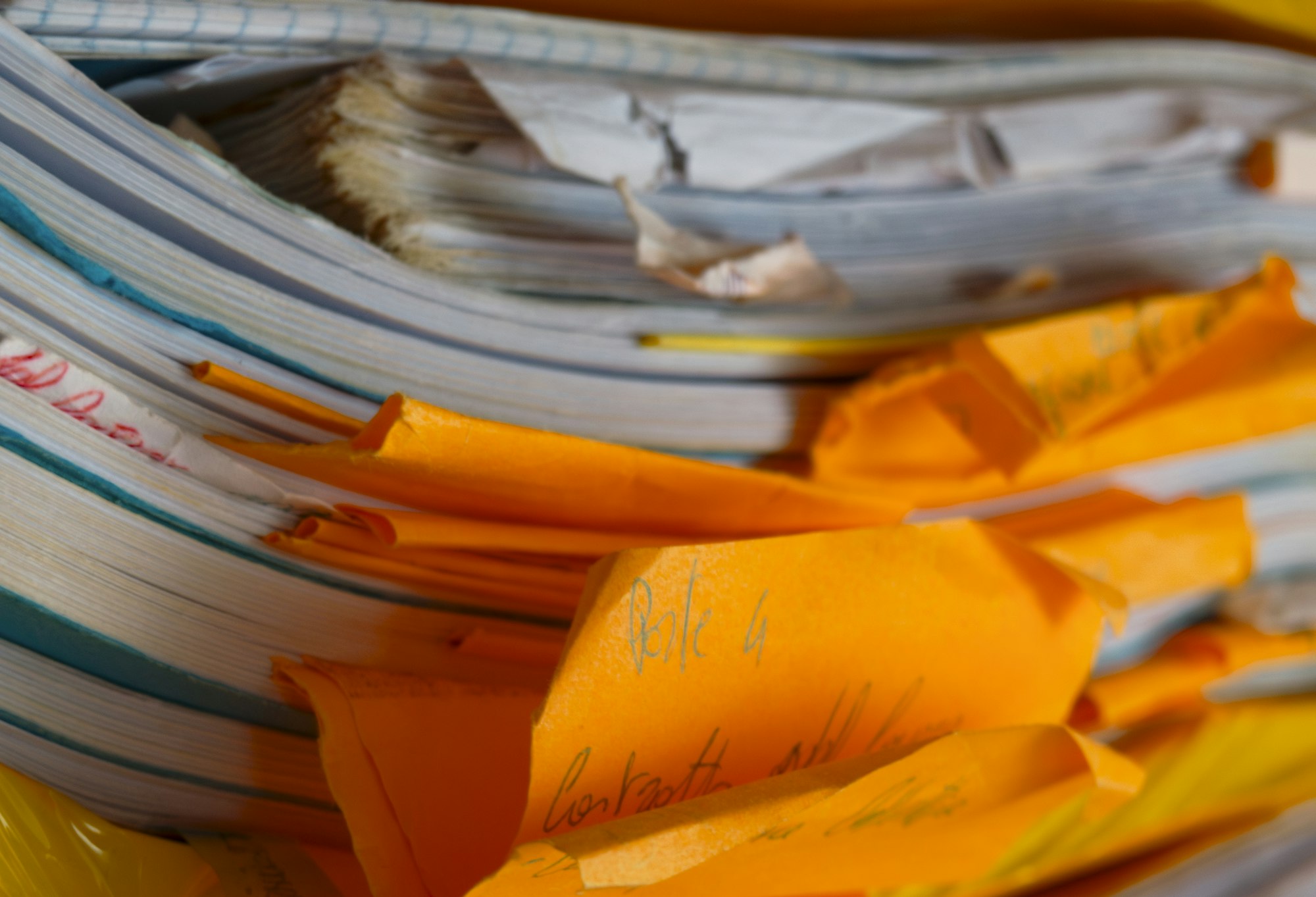 Close-up of an overflowing stack of paper files and orange folders