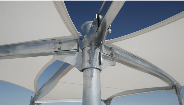 A close-up view of a sturdy steel post supporting a tensioned white fabric canopy, designed as a shade structure, stands against a clear blue sky. This fabric shade structure provides maximum sun protection, creating a comfortable environment in outdoor spaces like playgrounds or pool areas.