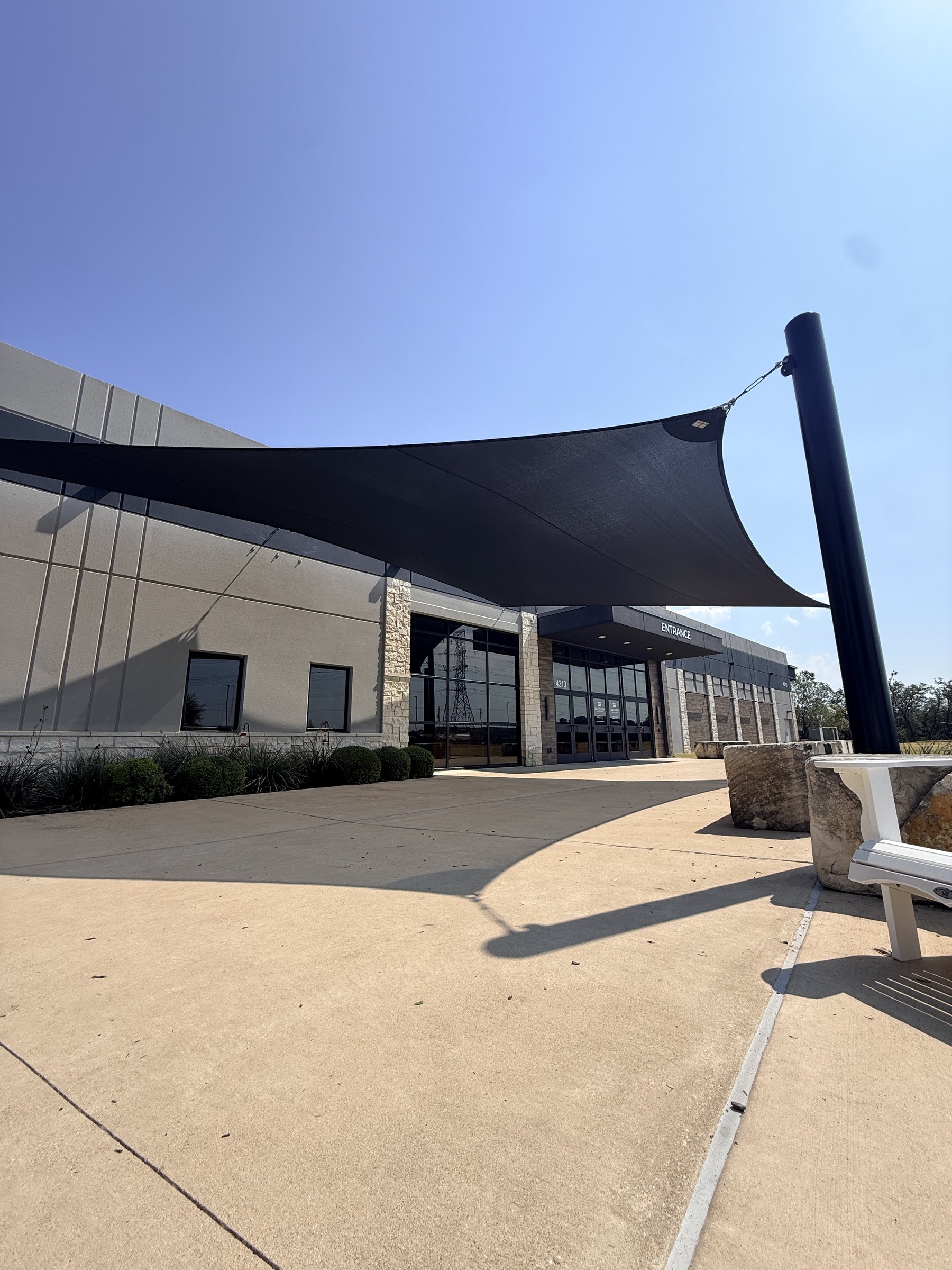 Five-point sail anchored to a steel post beside the entry walkway