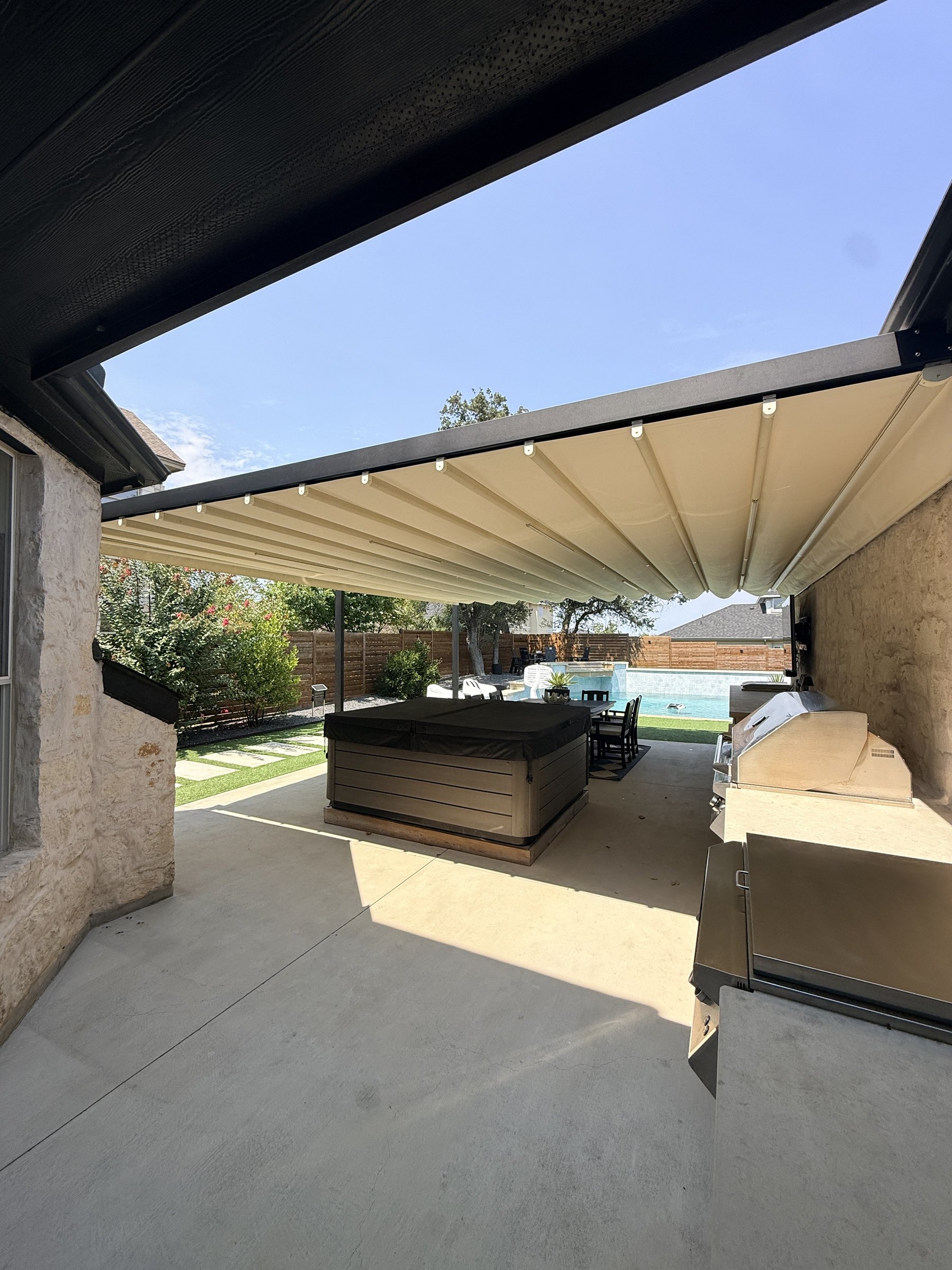 Palladia retractable pergola with Champagne canvas over the outdoor kitchen and spa