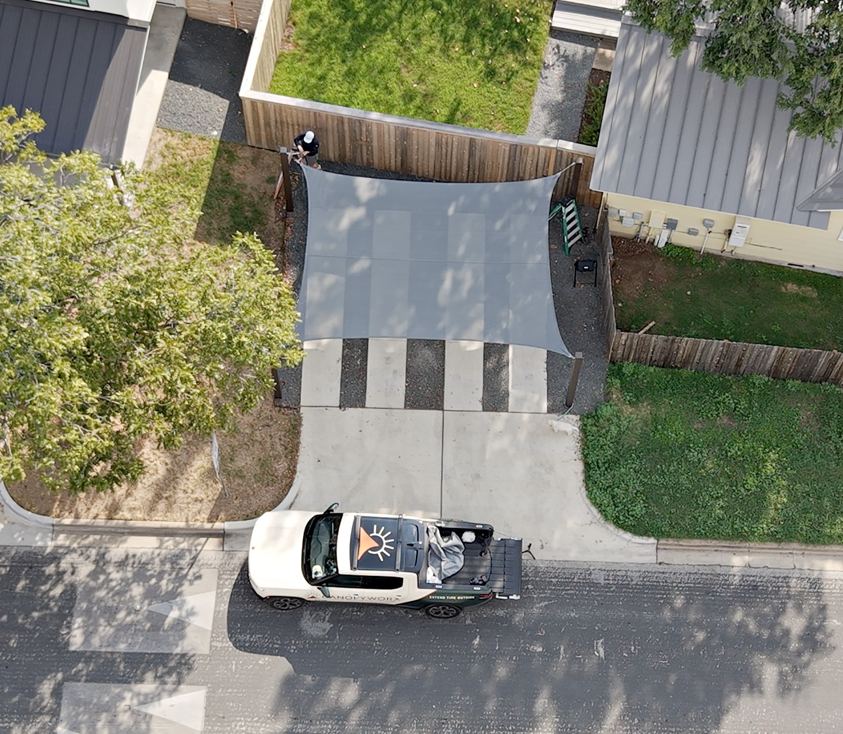 Drone view of the charcoal four-corner sail over a two-car parking pad