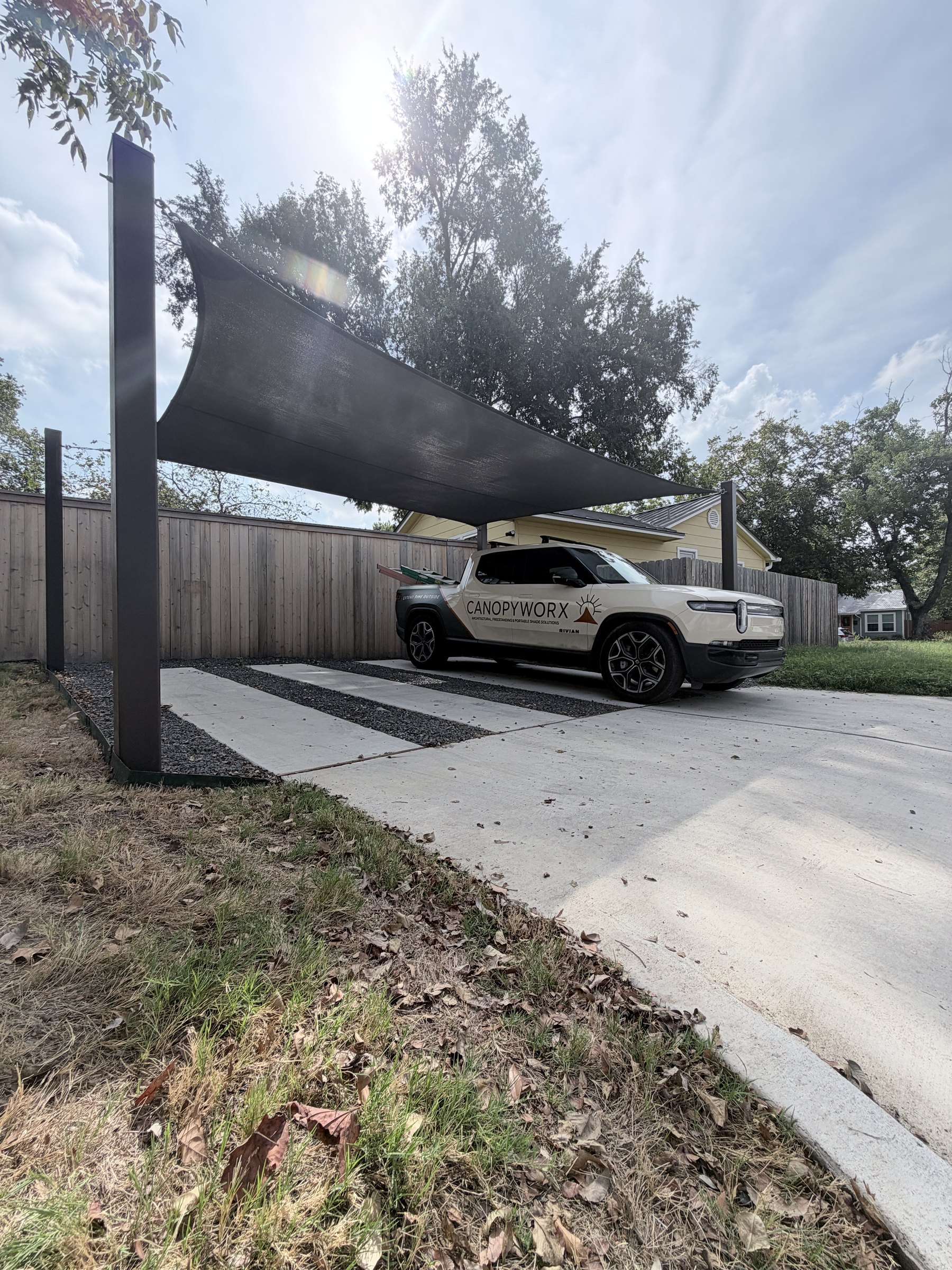 Carport sail with a high corner on a steel post and a truck parked beneath