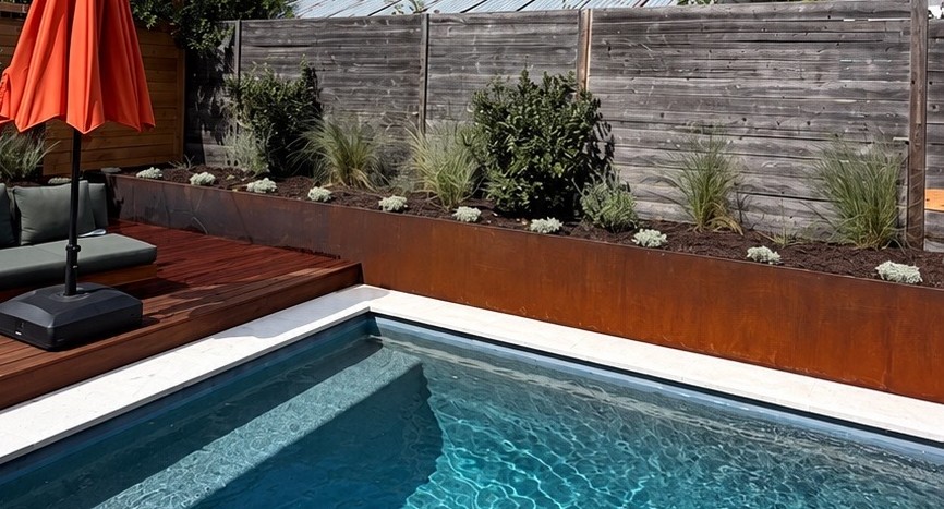 Weathering steel planter bed along the fence and pool, part of the backyard renovation by Collective Creative Outdoors