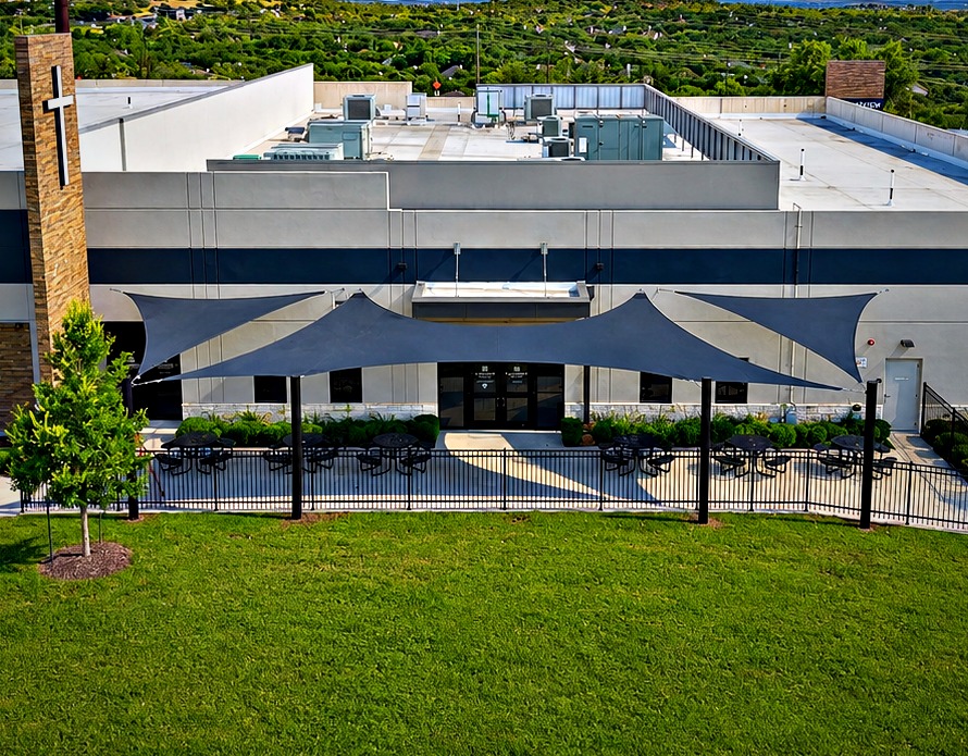 Wing-shaped shade sail wrapping the existing awning over the Lakeview Bible Church back terrace