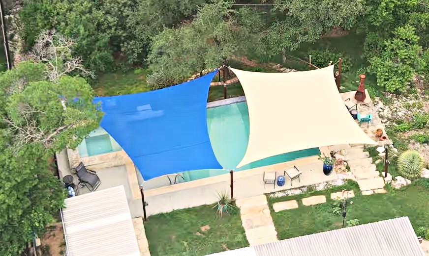 Blue and natural shade sails over a backyard pool in the Texas Hill Country