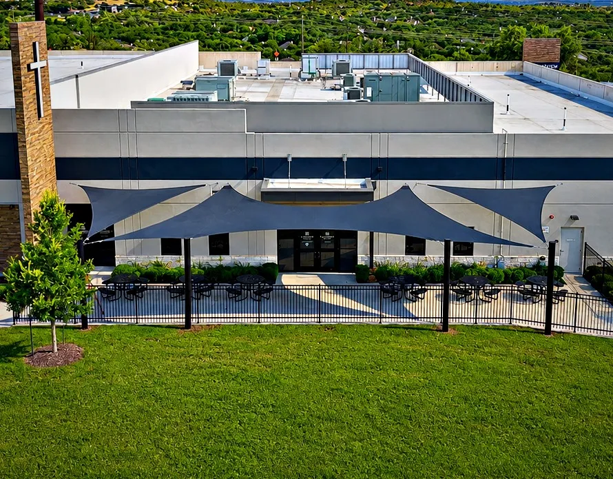 Wing-shaped shade sail wrapping the existing awning over the Lakeview Bible Church back terrace