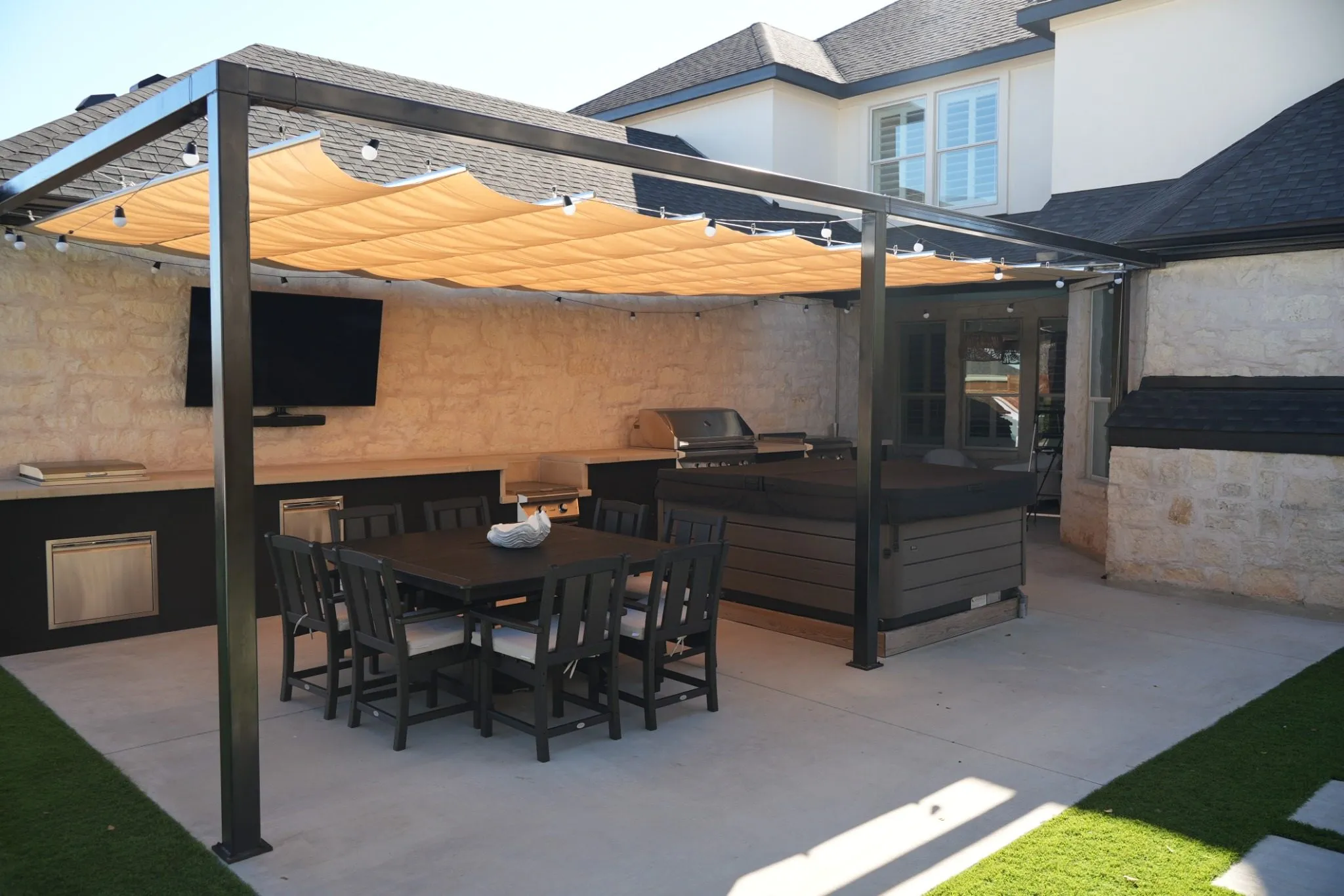 Tan Roman shade extended over the patio dining area and outdoor kitchen