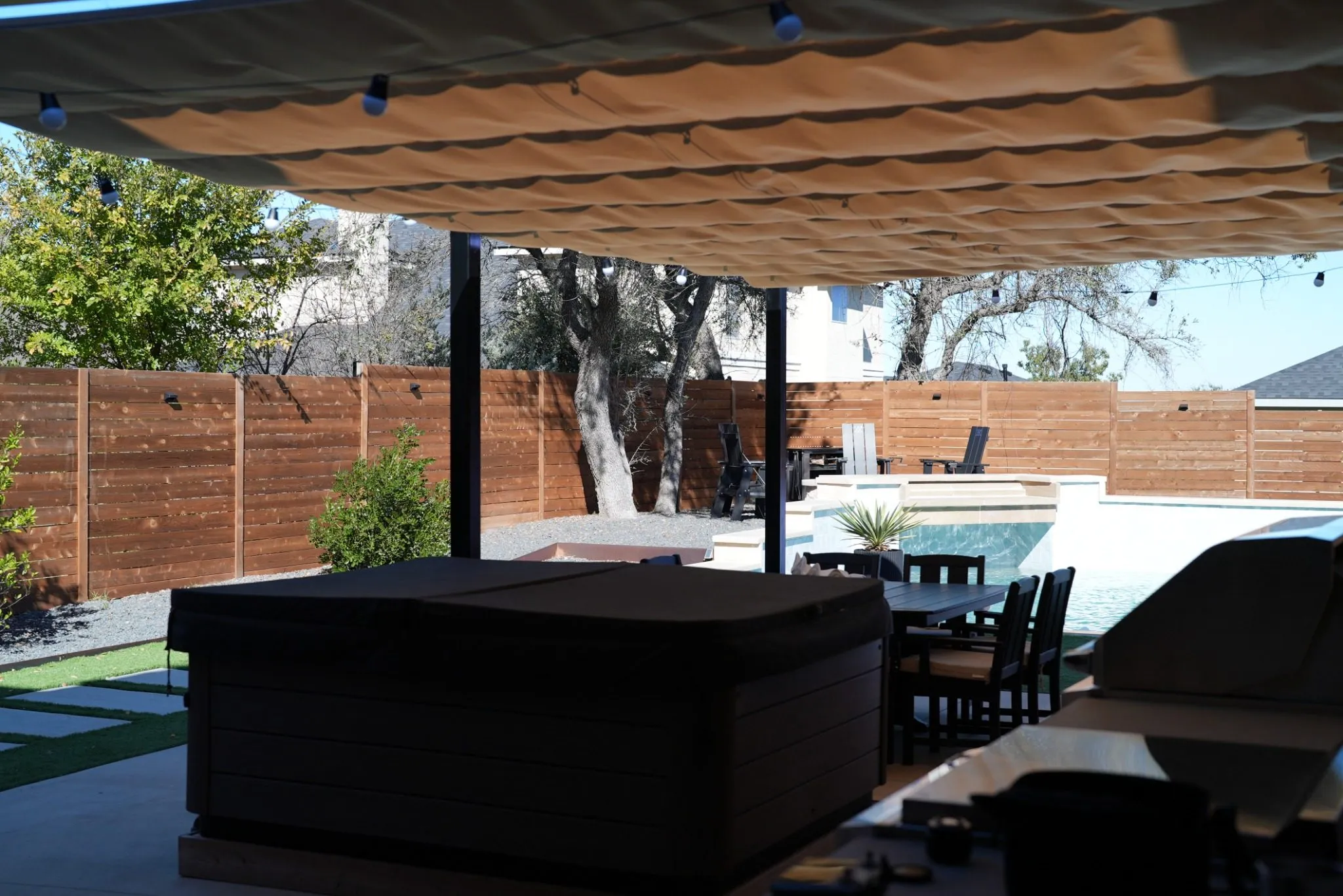 View from under the Roman shade toward the hot tub, pool, and wood fence
