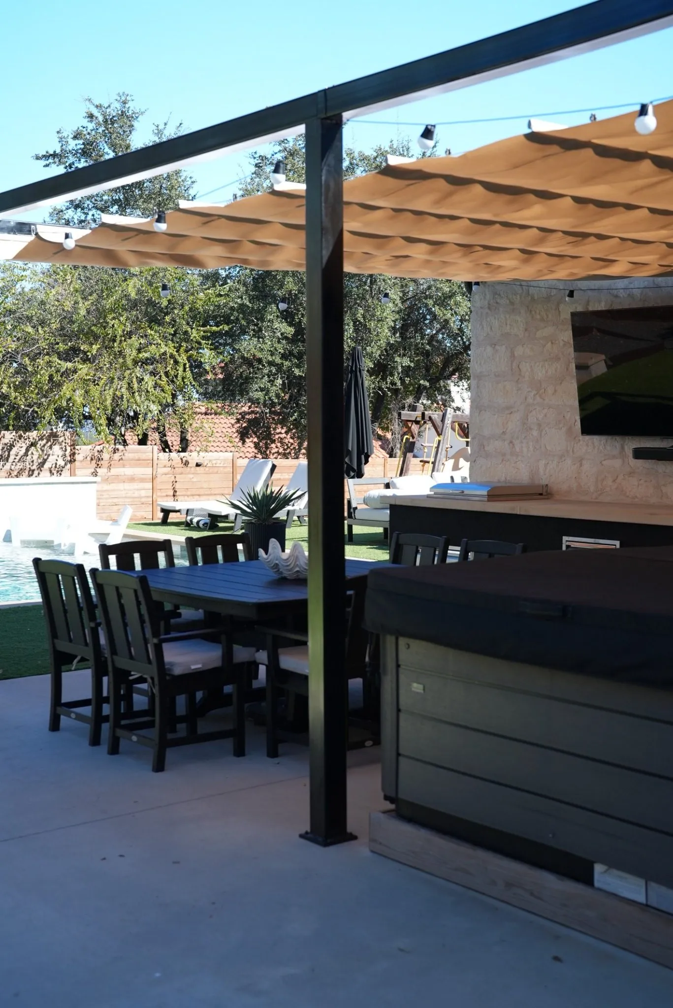 Folds of the Roman shade along the steel frame above the hot tub, with the pool beyond