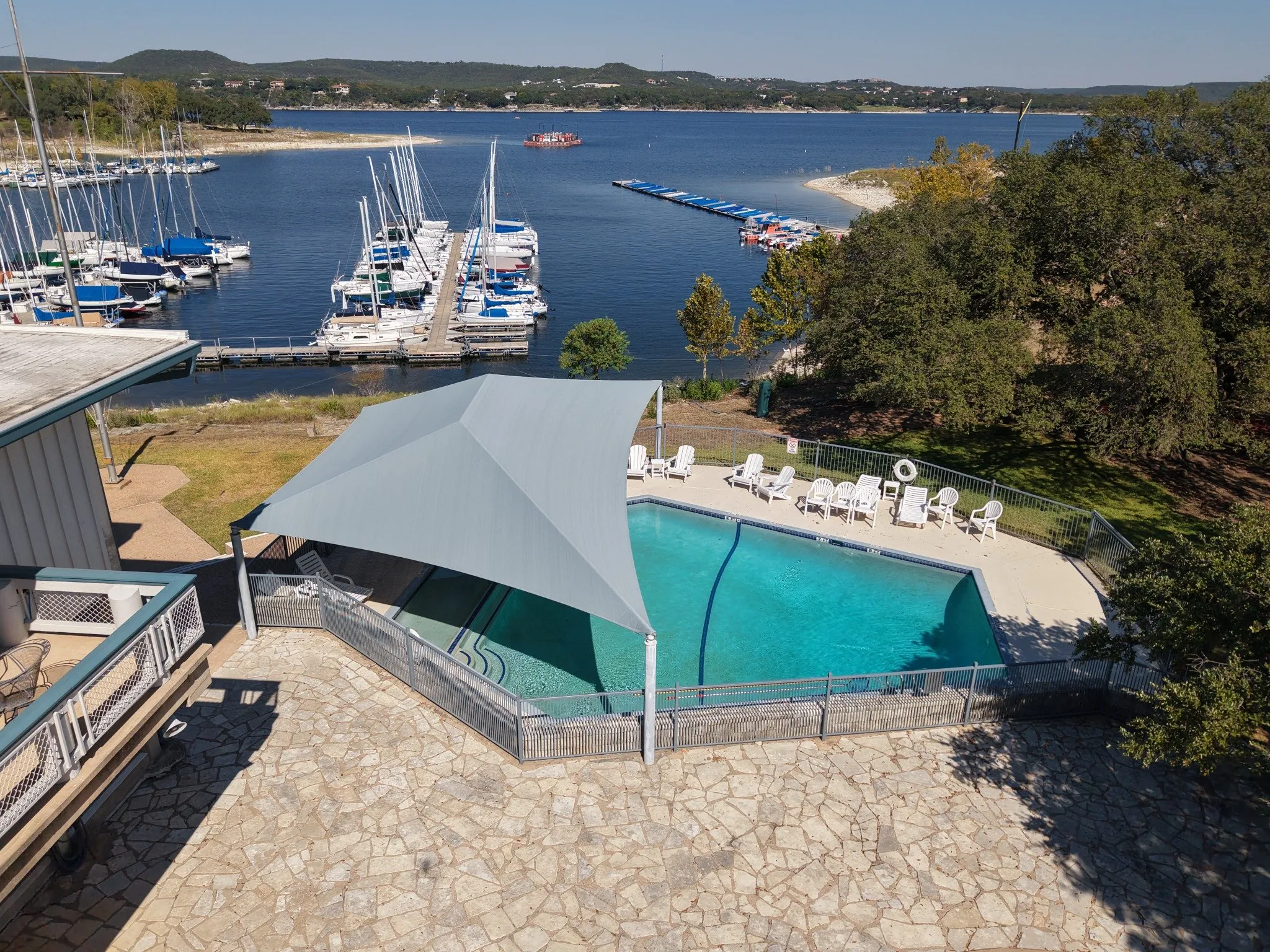 Freestanding shade over one end of the Austin Yacht Club pool, with the marina and Lake Travis behind