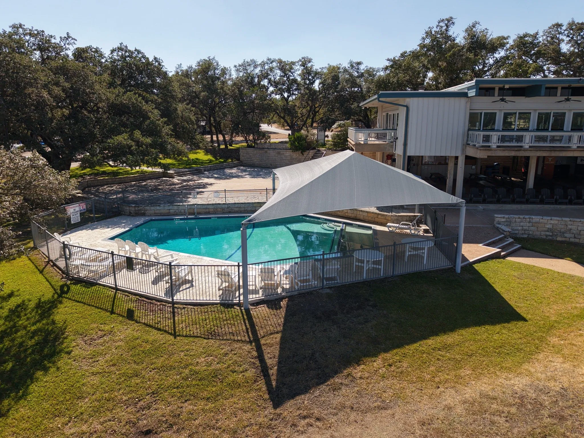 The freestanding shade structure over the pool, seen from the lawn beside the clubhouse
