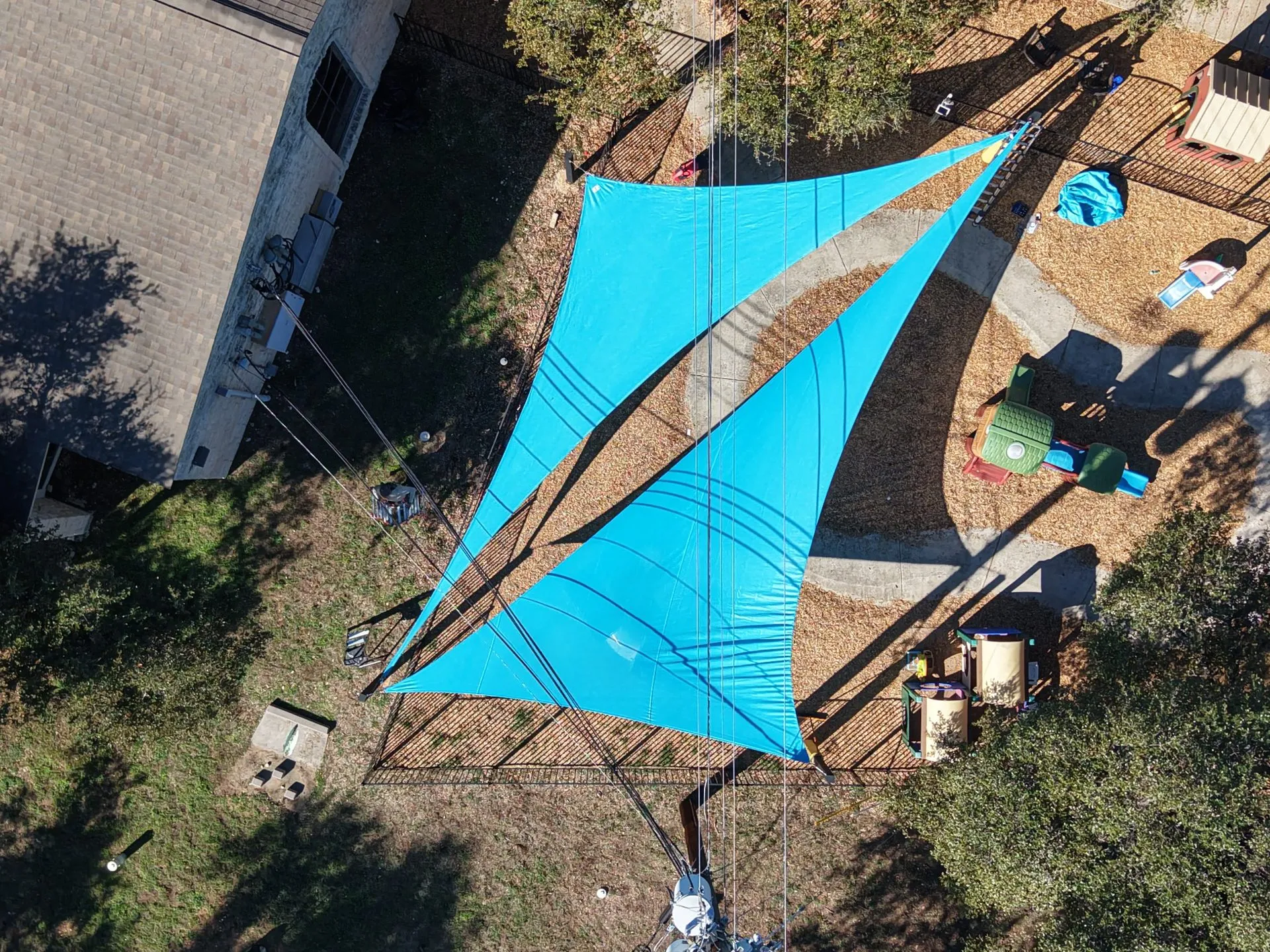 Overhead drone view of the two blue triangle sails shading the preschool playground