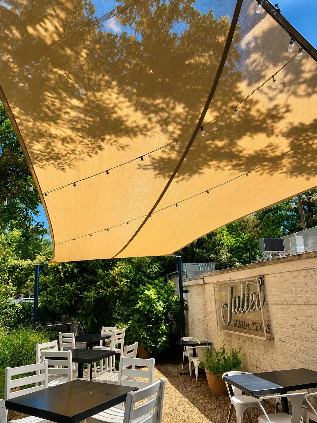 Tree shadows on the yellow sail above the Juliet patio tables