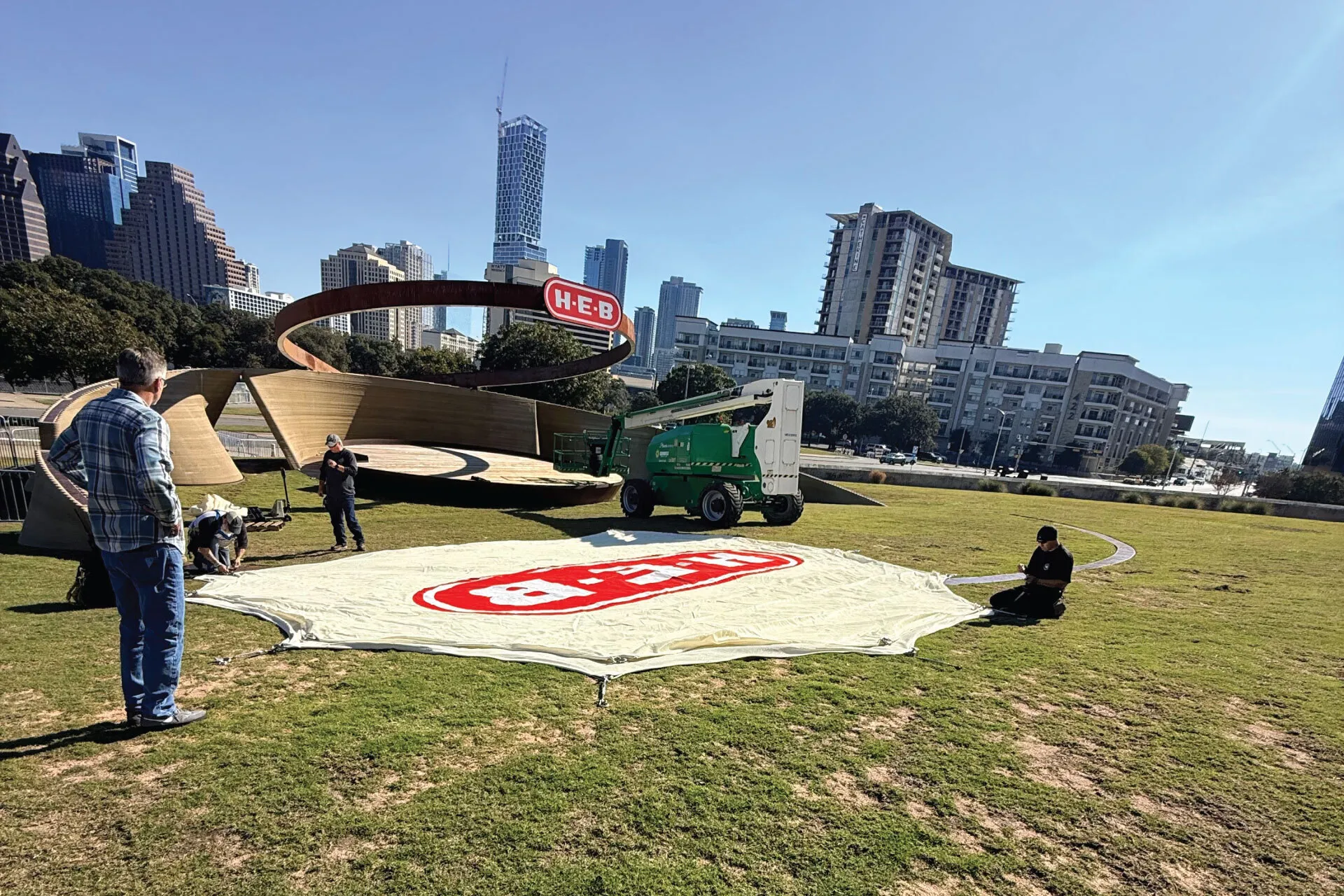 The crew lays out the H-E-B canopy on the lawn before raising it over the amphitheater