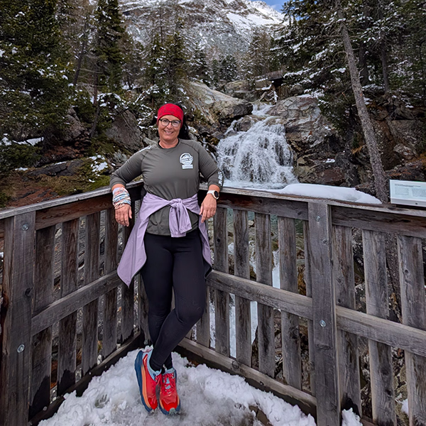 Nadine Wienecke steht auf einer Holzbrücke vor einem Wasserfall im Winter mit Schnee