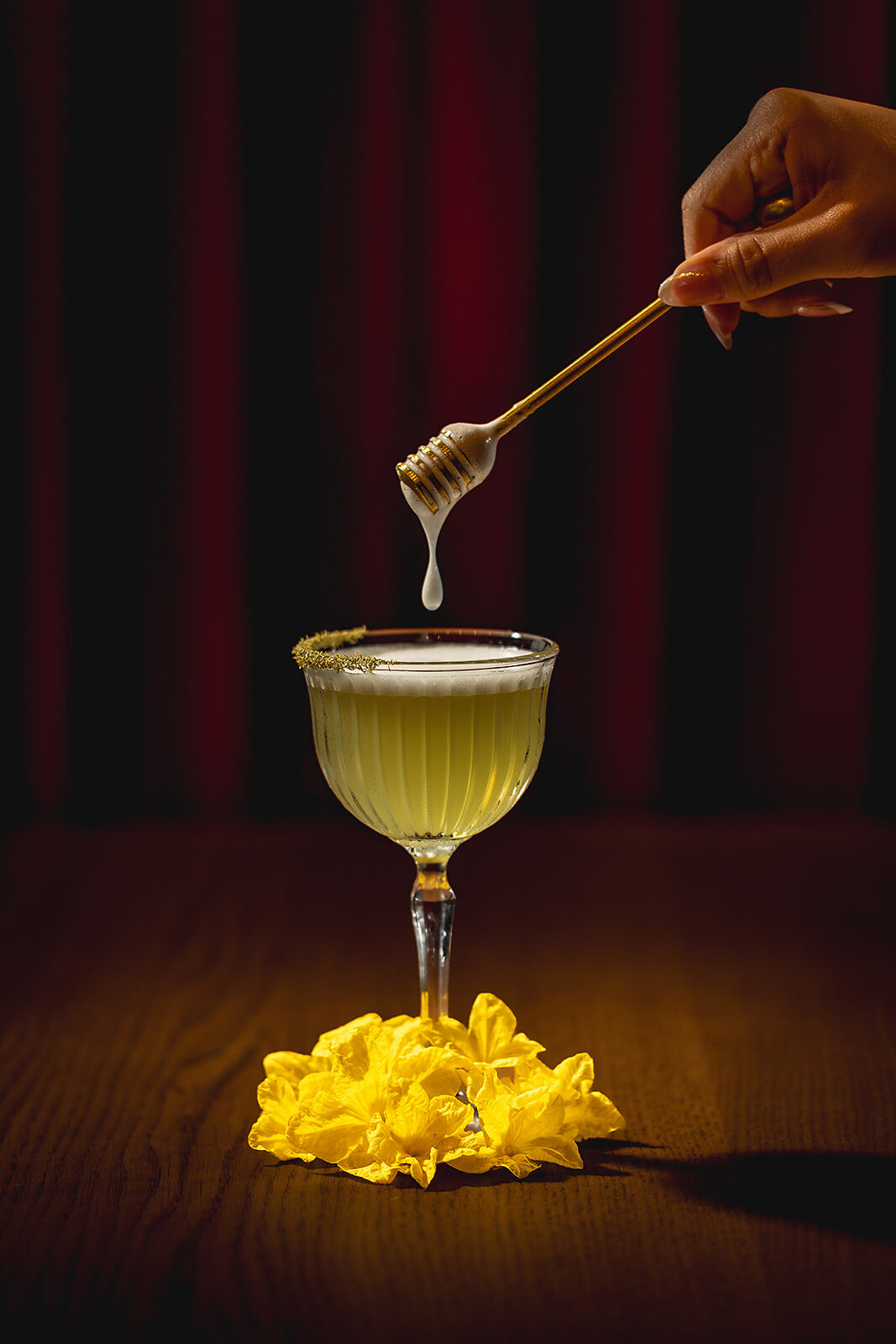 A cocktail being finished with honey from a dipper