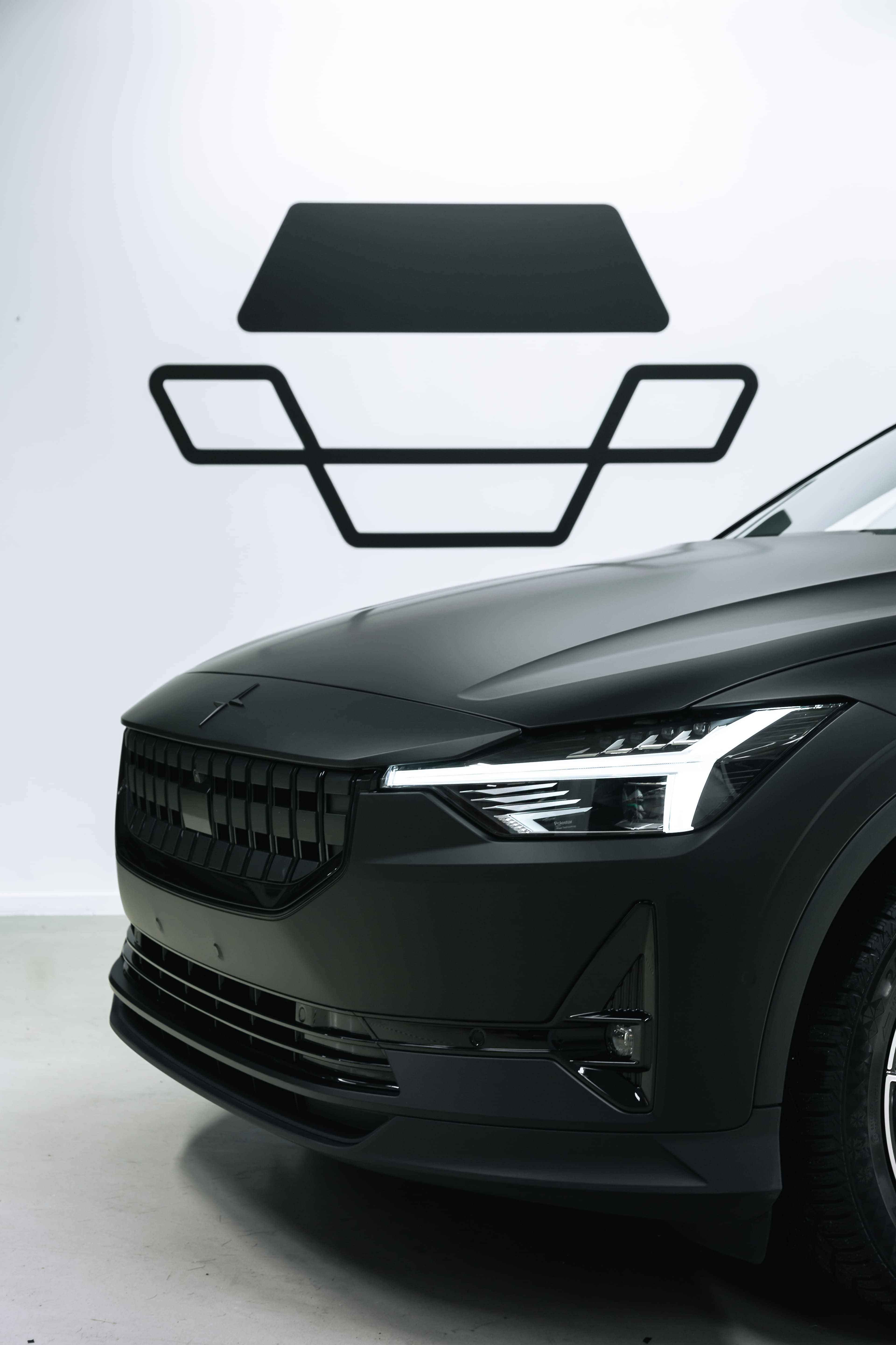 Detaljert front av svart Polestar 2 elbil med lysende LED-lys og Polestar-logo på motorhuven.