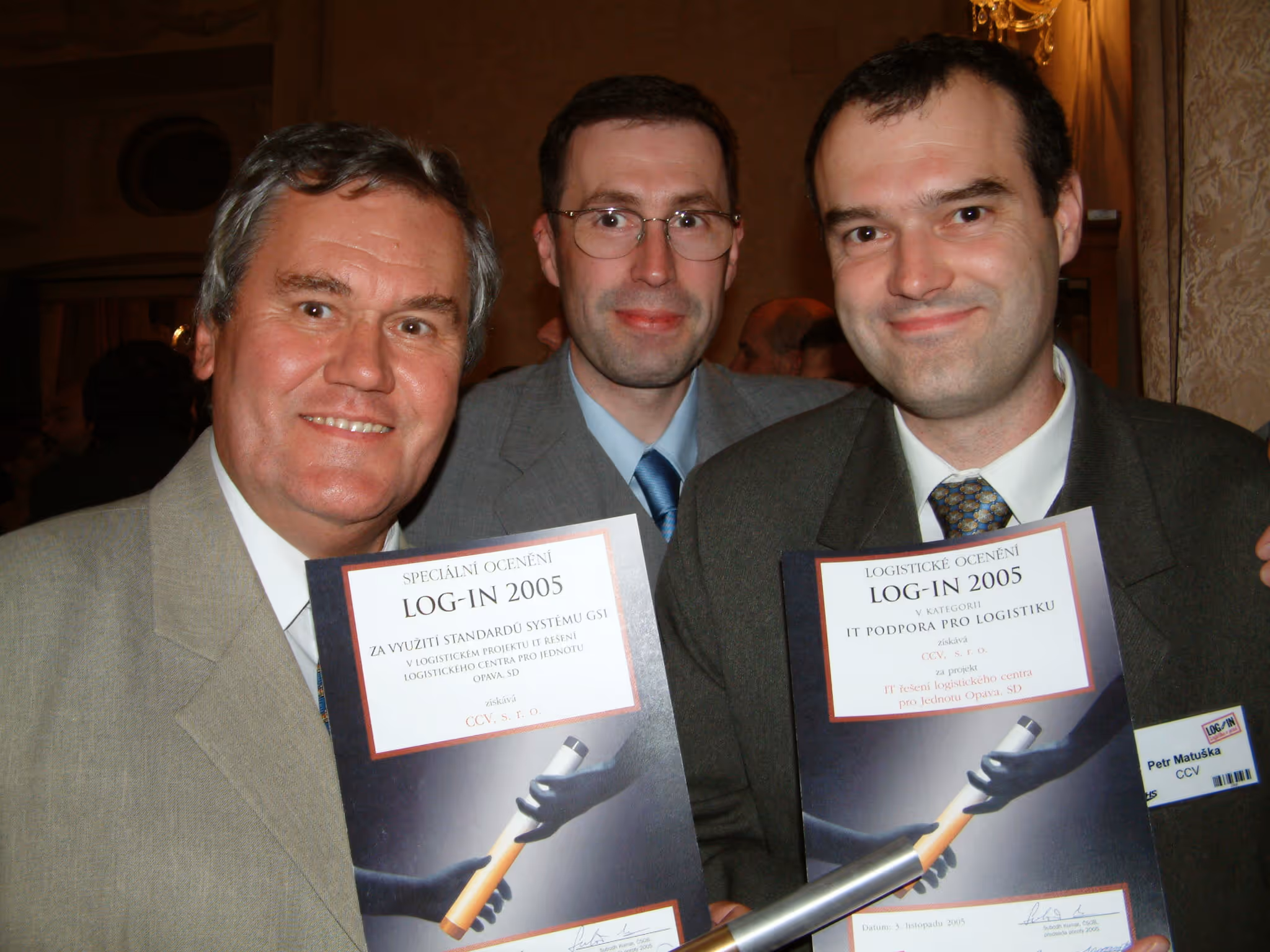 Tři muži v oblecích drží ocenění LOG-IN 2005 na logistiku a IT podporu.