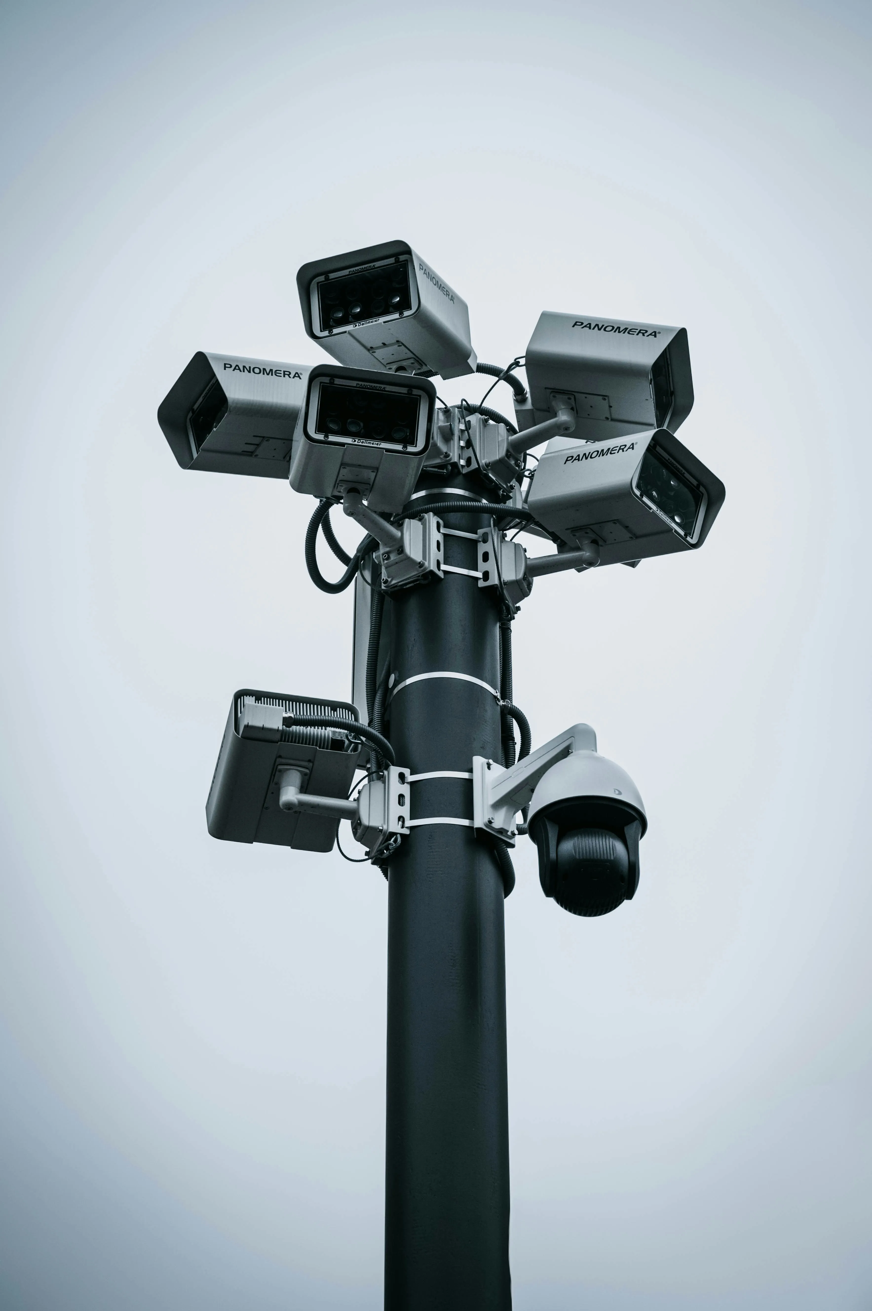 Black pole with multiple silver Panomera security cameras pointing in different directions against a gray sky.