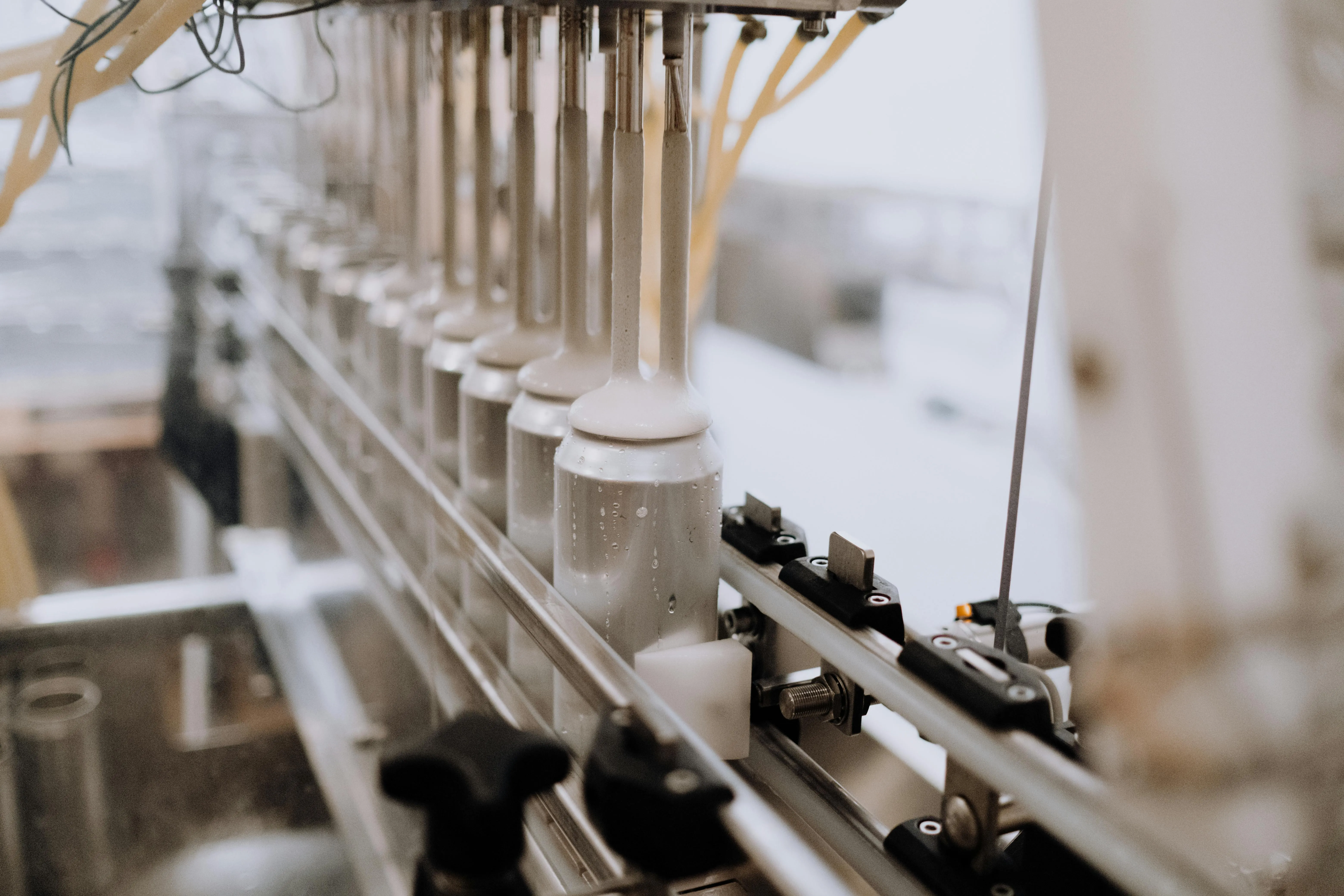 Machine filling aluminum cans with foaming liquid in a production line.