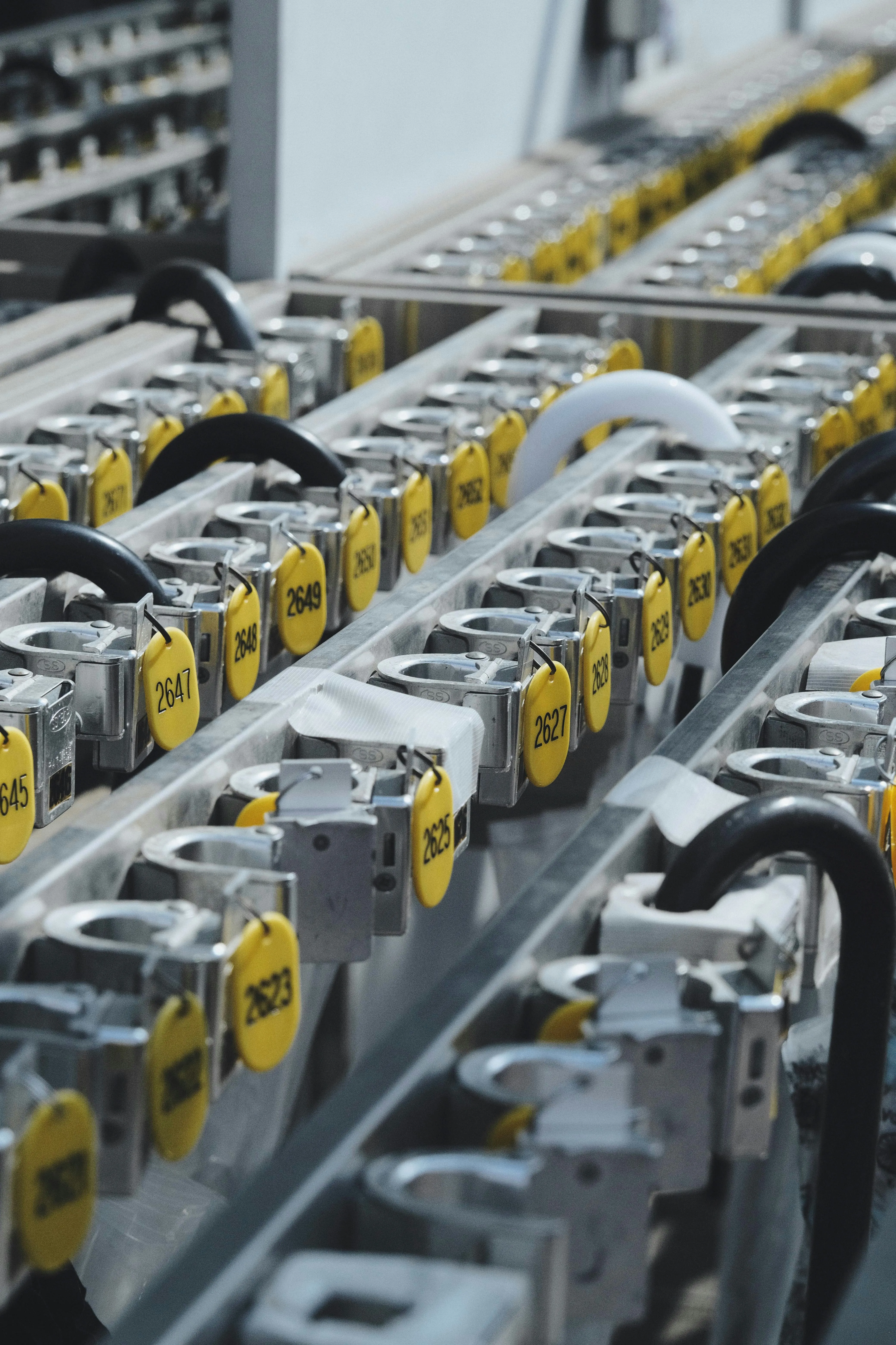 Rows of metal locks with yellow number tags and black or white U-shaped shackle handles.