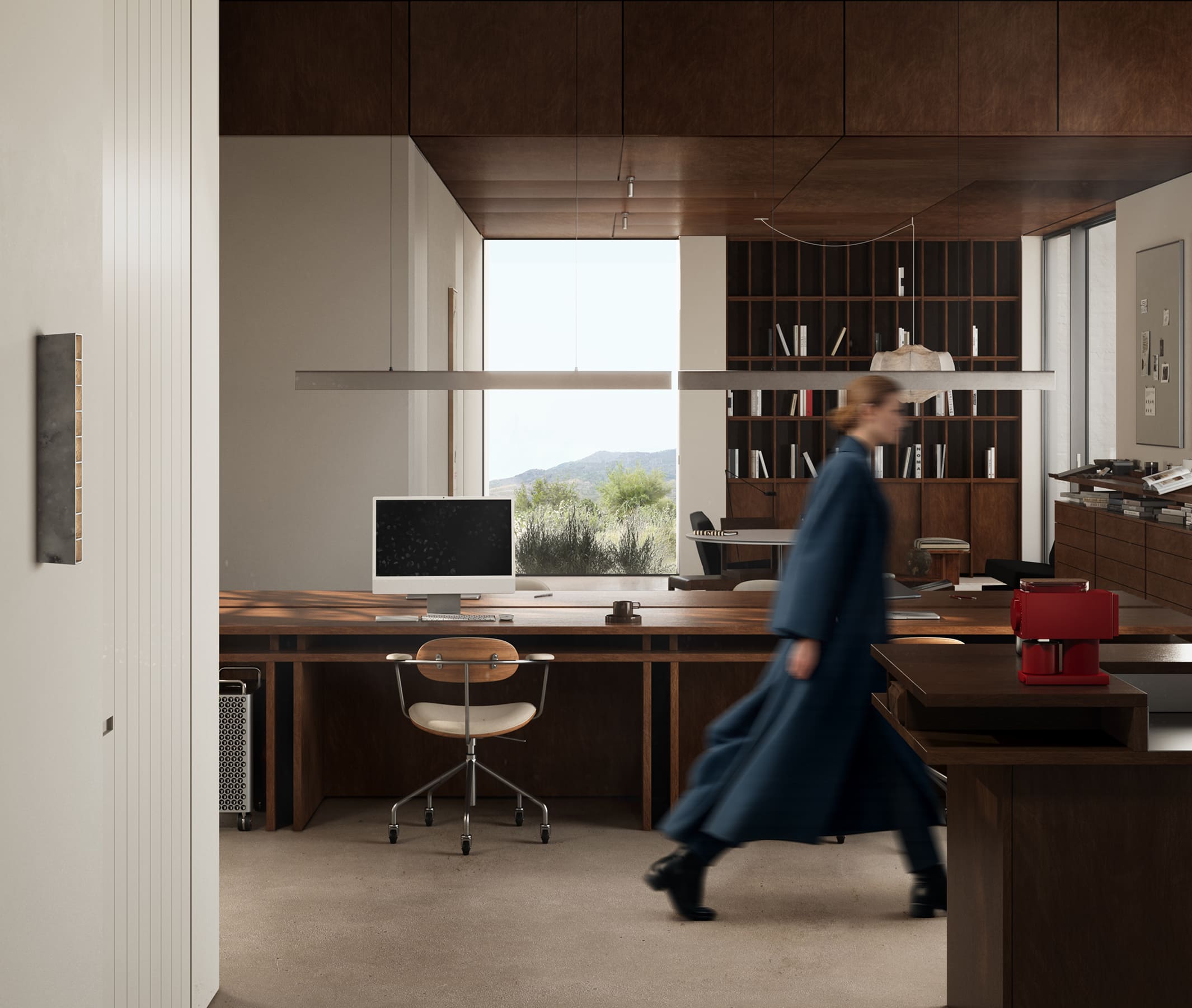 Modern office with wooden shelves, computer on desk, large window, and a blurred person walking.