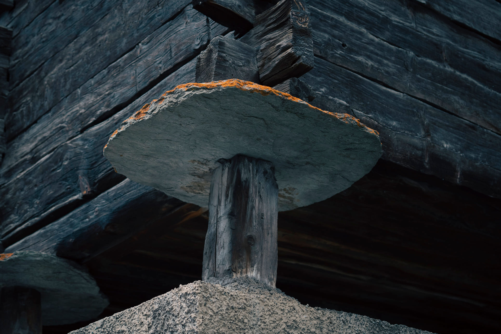 Two rustic clay pots against a cracked textured wall, one supported by a wooden frame.