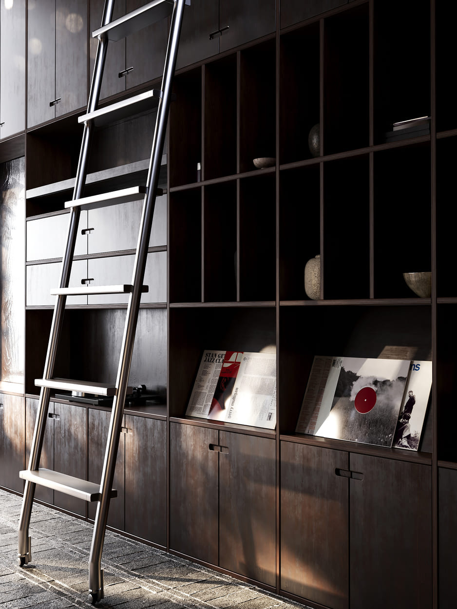 Tall dark wooden bookshelf with closed cabinets at the bottom and open shelves above, some holding decorative objects and records, with a tall metal rolling ladder leaning against it on a stone floor with sunlight casting shadows.